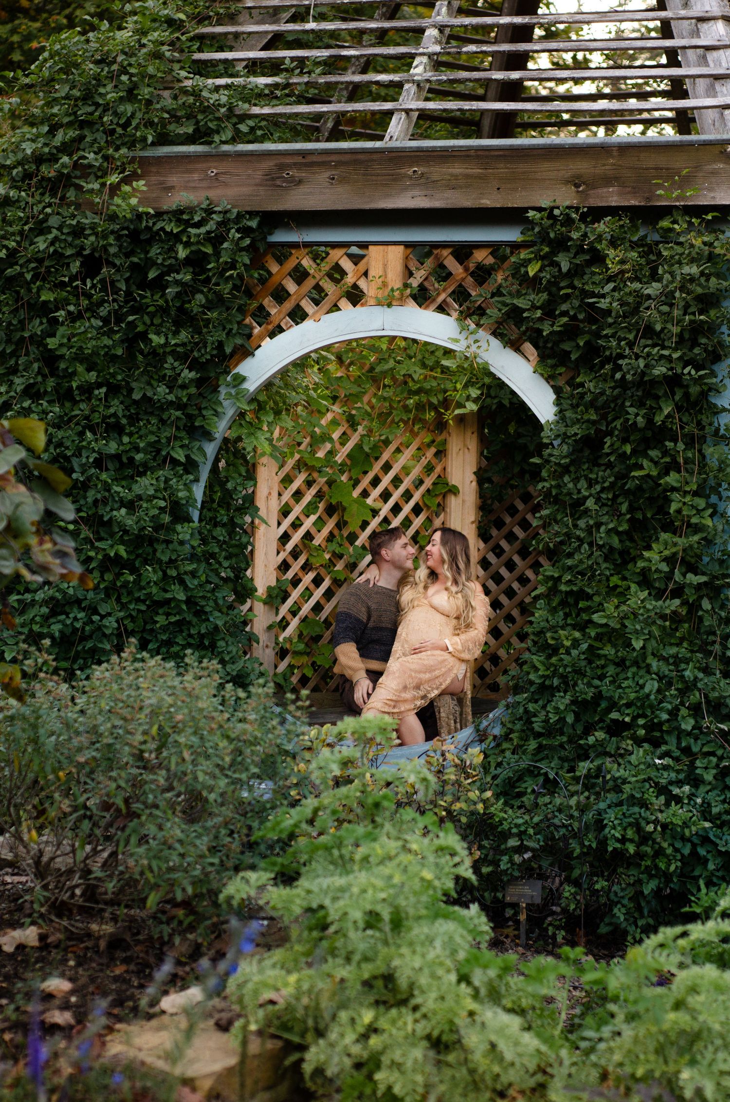 Romantic garden scene with couple posing under a wooden lattice archway. Maternity photos by KM Conceptions Photography in Columbus, OH.