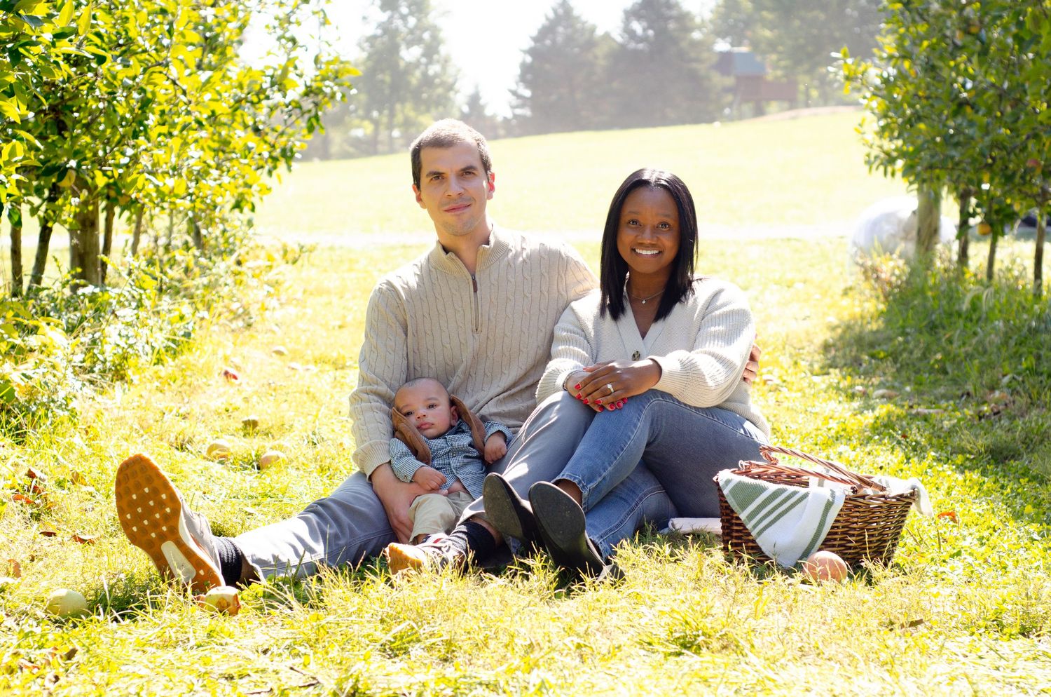 A family relaxes together on grass in a sunny outdoor setting. Family photos by KM Conceptions Photography in Columbus, OH.