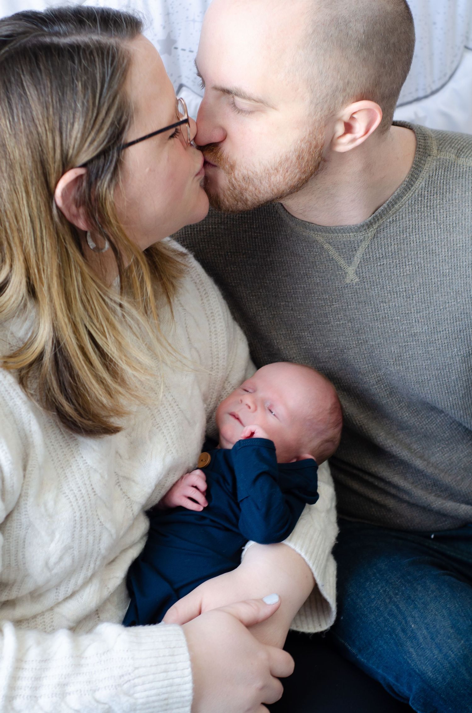 An intimate family moment captured on a soft gray background in natural lighting. Newborn photos by KM Conceptions Photography in Columbus