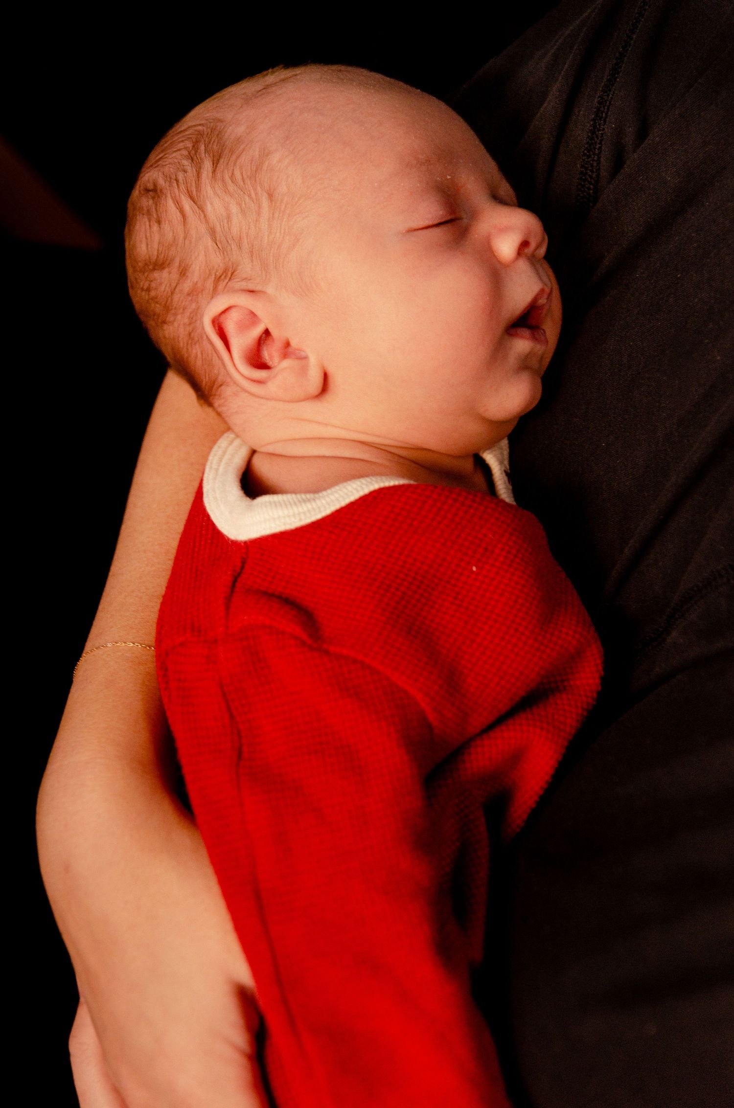 Sleeping baby in red outfit captured in profile view. Newborn photography in Columbus, OH