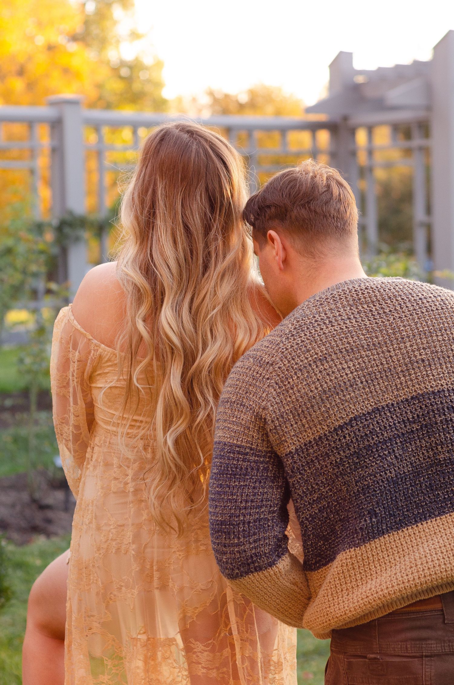 Couple in autumn setting embracing while looking at sunset. Maternity photos by KM Conceptions Photography in Columbus, OH.