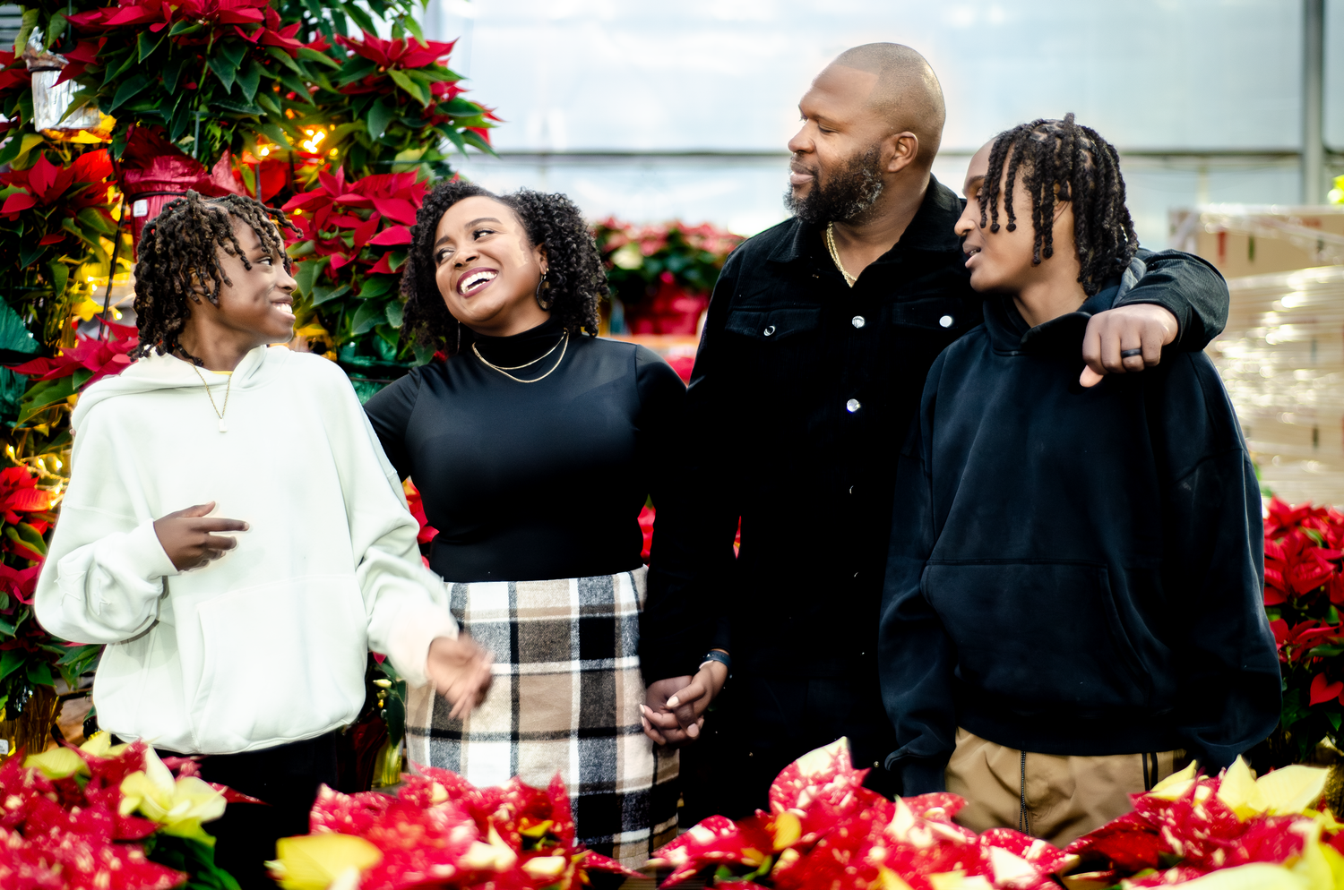 Holiday photo session with vibrant red poinsettias and festive decorations in the background. Photos by KM Conceptions Photography.