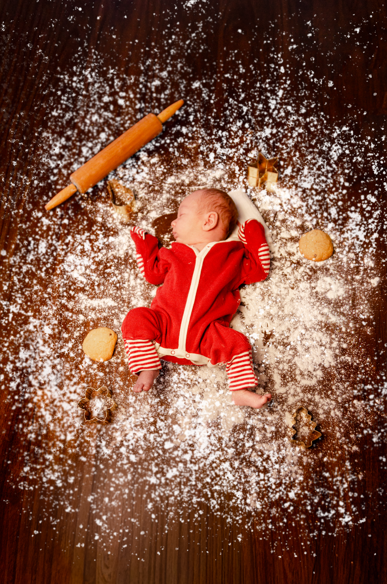 Holiday scene with red outfit and scattered flour against dark wooden background. Newborn photography in Columbus, OH