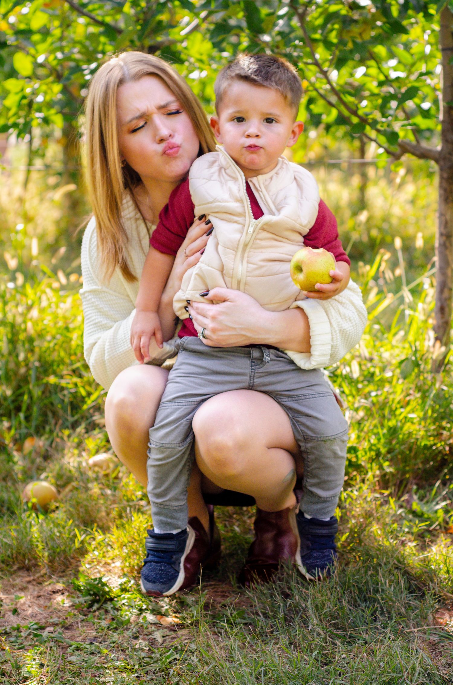Candid outdoor photo sequence showing playful moments with a toddler holding fruit. Family photos by KM Conceptions Photography in Columbus