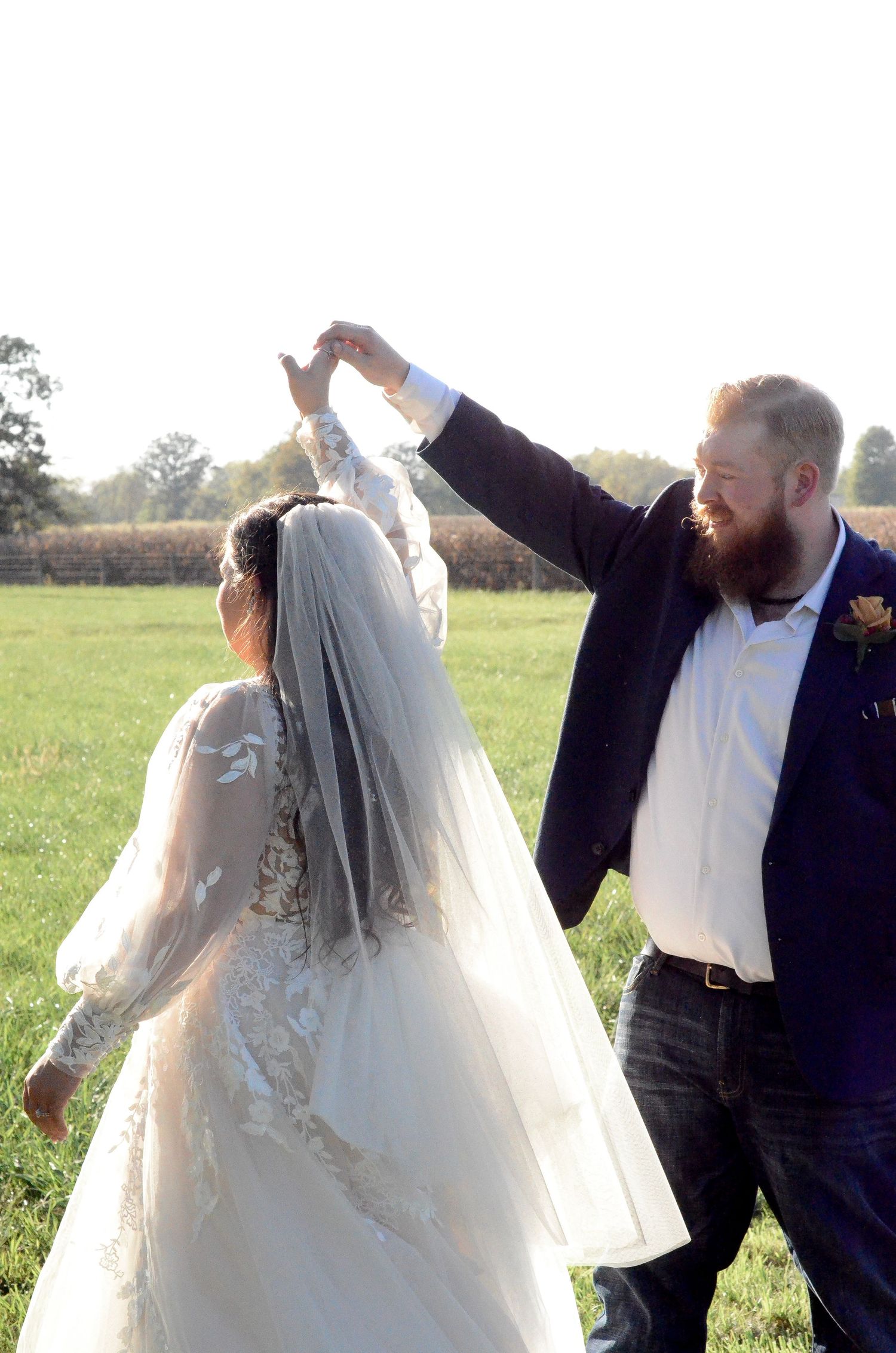 Newlyweds dancing and twirling together in an outdoor field setting. Wedding photos by KM Conceptions Photography in Columbus, OH.