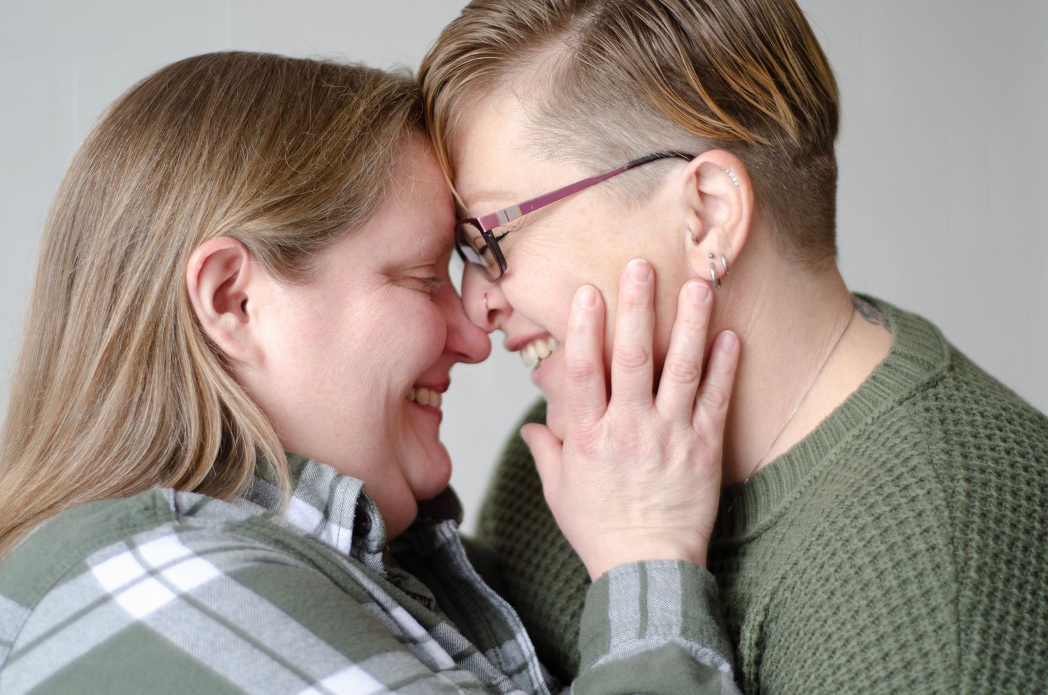 Intimate close-up of couple sharing tender moment against neutral background.