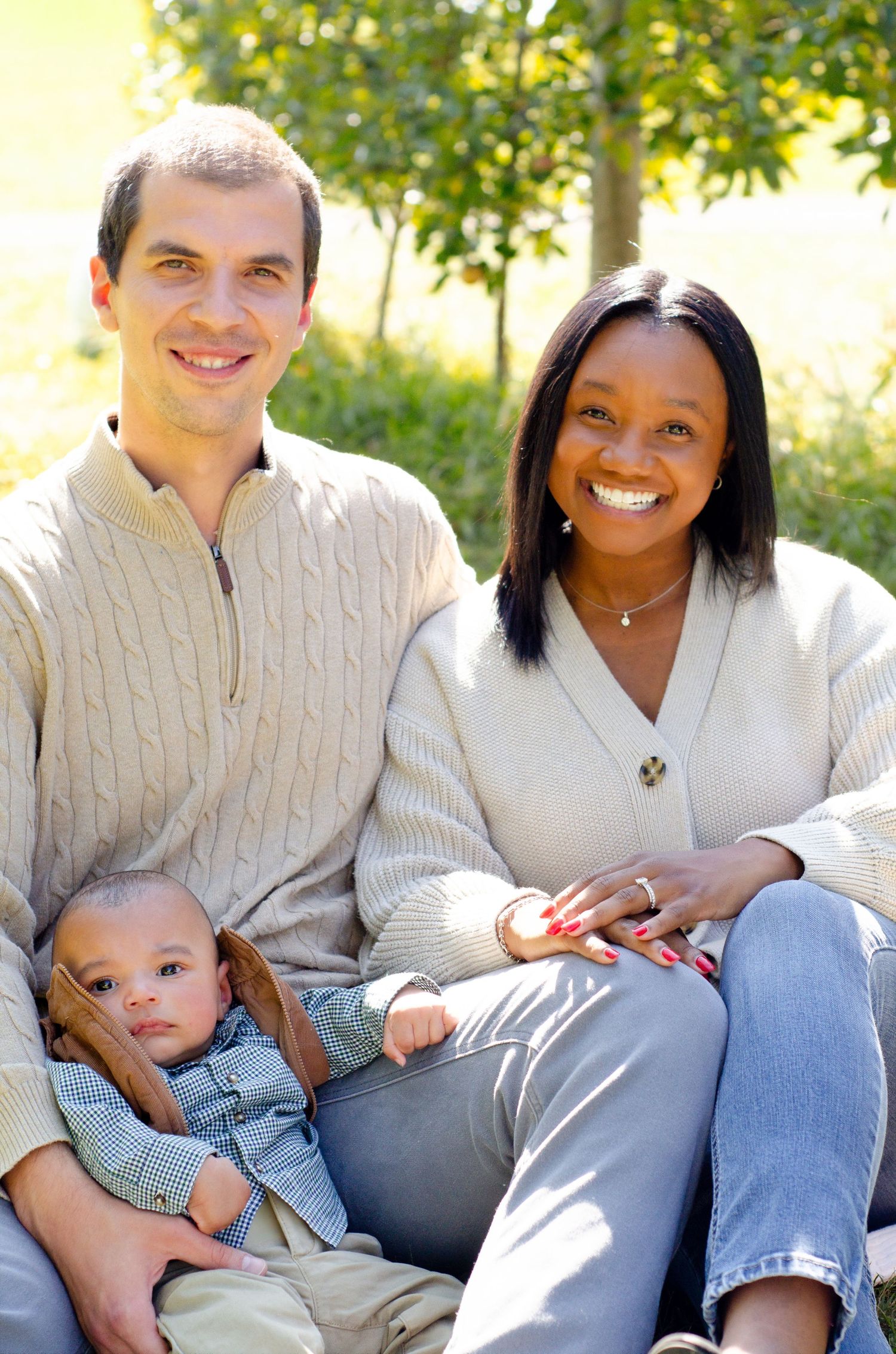 A family sits together on grass during an outdoor photo session. Family photos by KM Conceptions Photography in Columbus, OH.