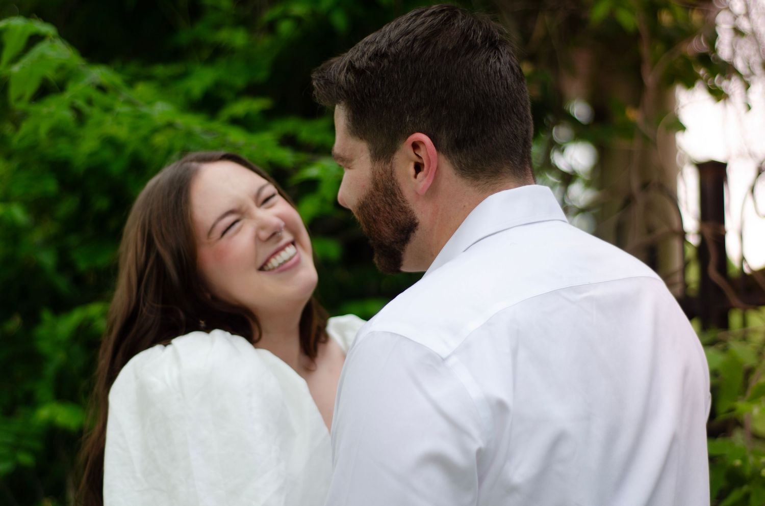 Romantic couple sharing joyful moments under green tree canopy.