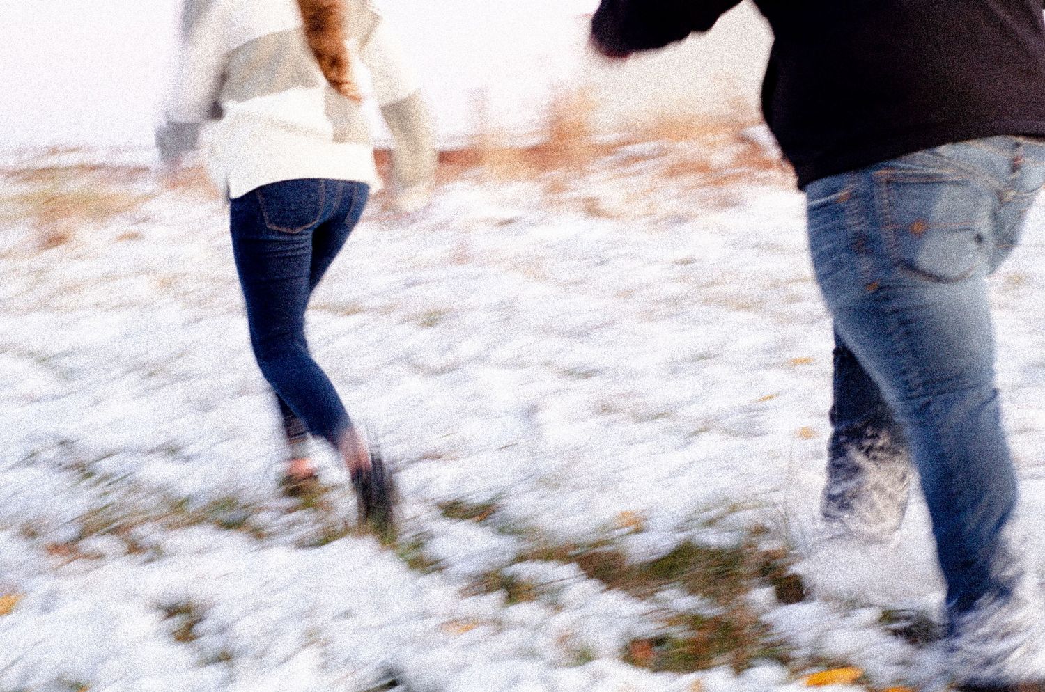 Couple walking together through snowy ground during a winter photo session.