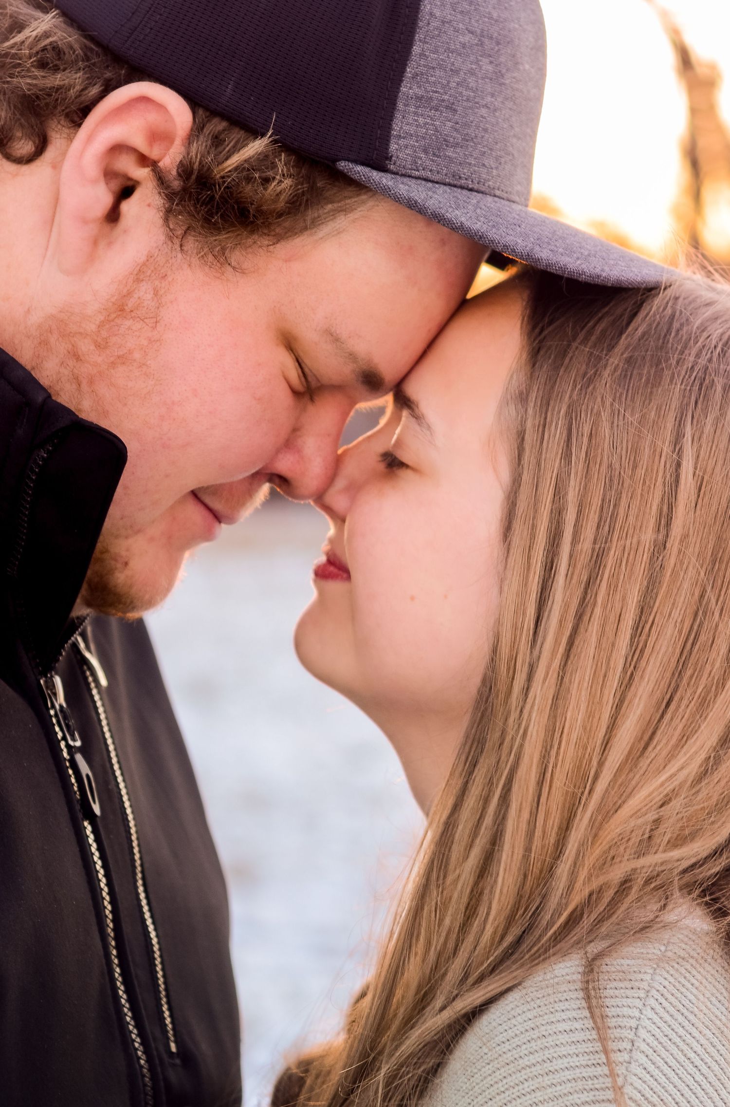 Romantic couple sharing an intimate close-up moment against a light background.