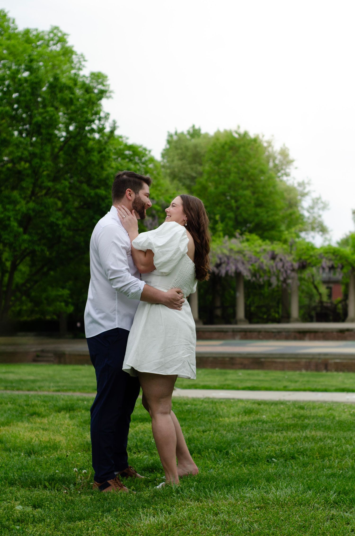 A romantic moment shared on a grassy lawn with white columns in the background.