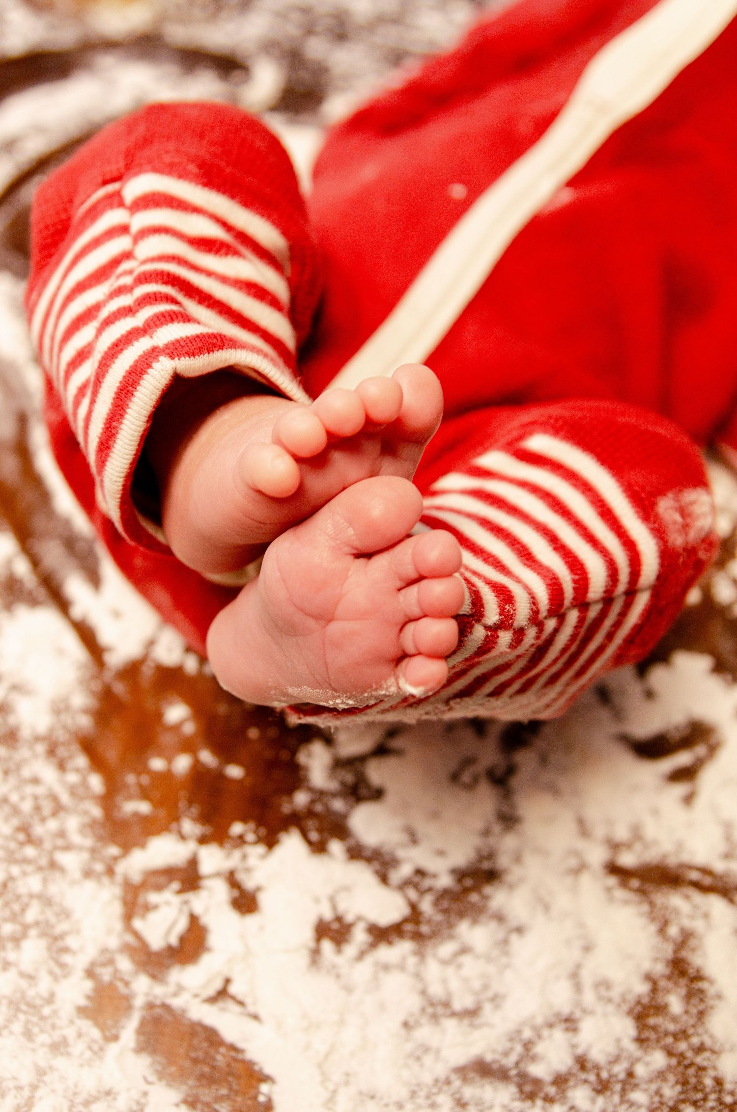 Close-up of tiny feet in red and white striped pajamas against a flour-dusted surface. Newborn photography in Columbus, OH