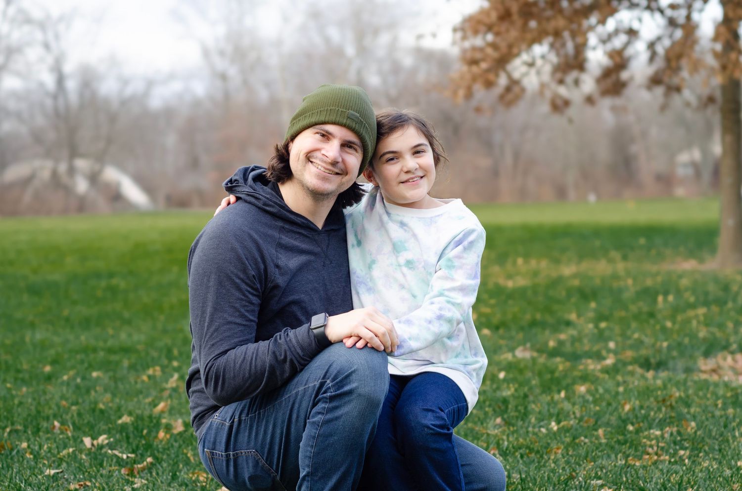 Autumn outdoor gathering on grass with bare trees in background.