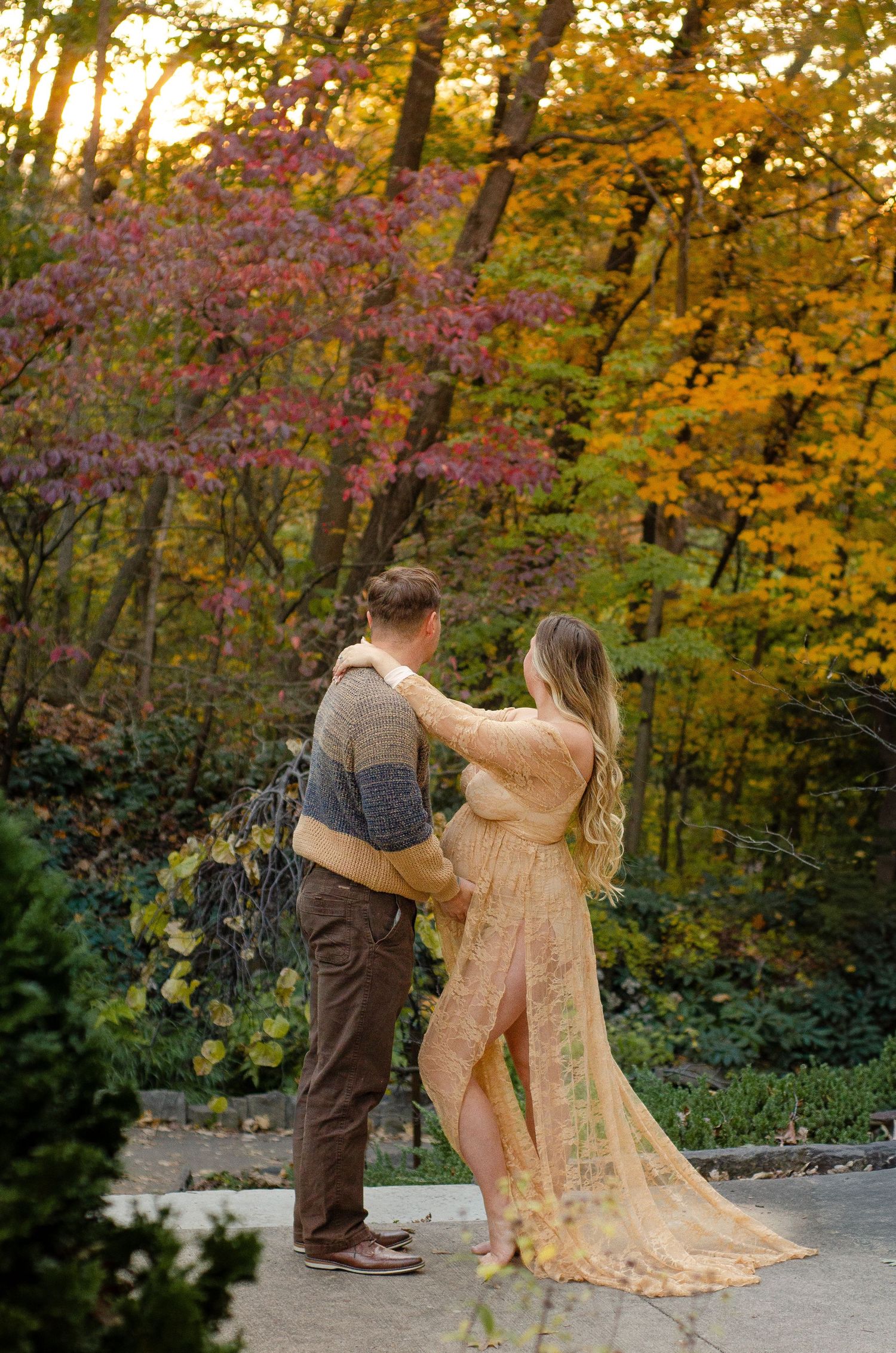 Dancing couple twirls on a stone path surrounded by vibrant fall colors. Maternity photos by KM Conceptions Photography in Columbus, OH.