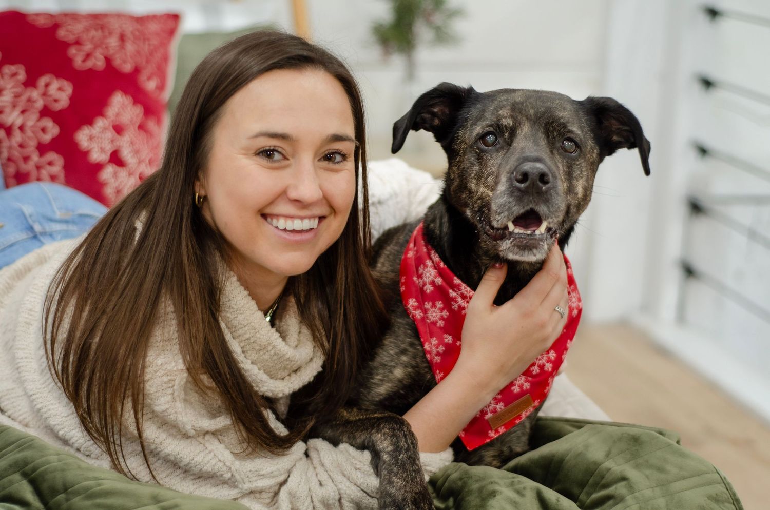 A cheerful moment with a black dog wearing a festive red bandana on a green cushion.