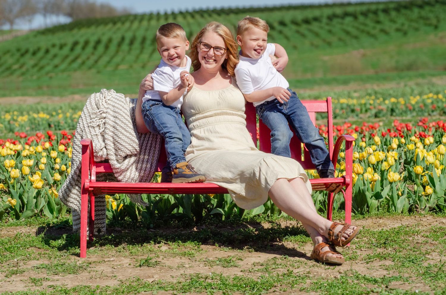 Family resting on a red bench surrounded by blooming yellow daffodils.