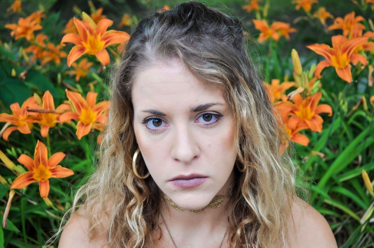 A portrait against vibrant orange daylilies in a garden setting.