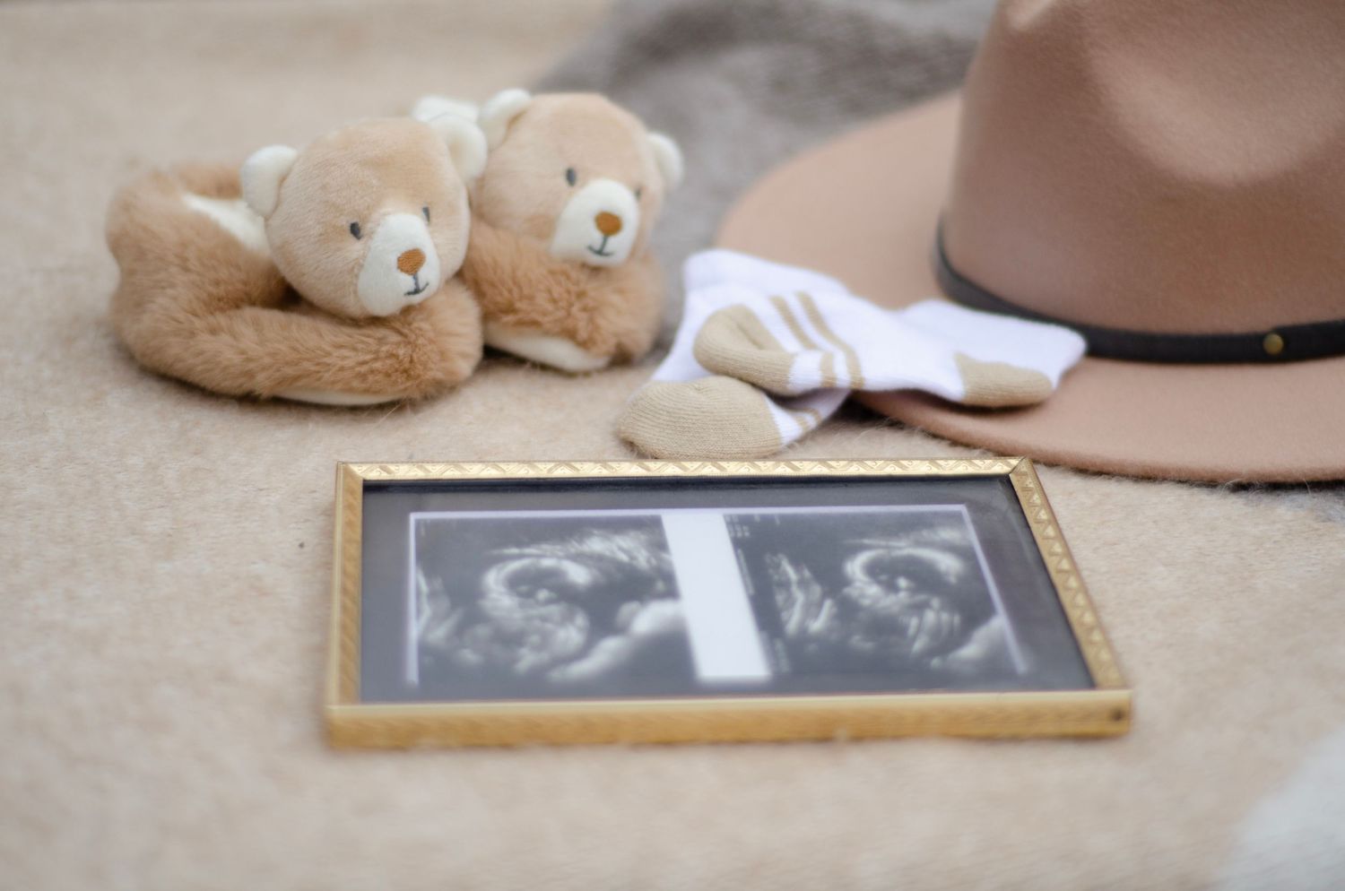 Ultrasound photo framed with plush teddy bears and hat for pregnancy announcement.