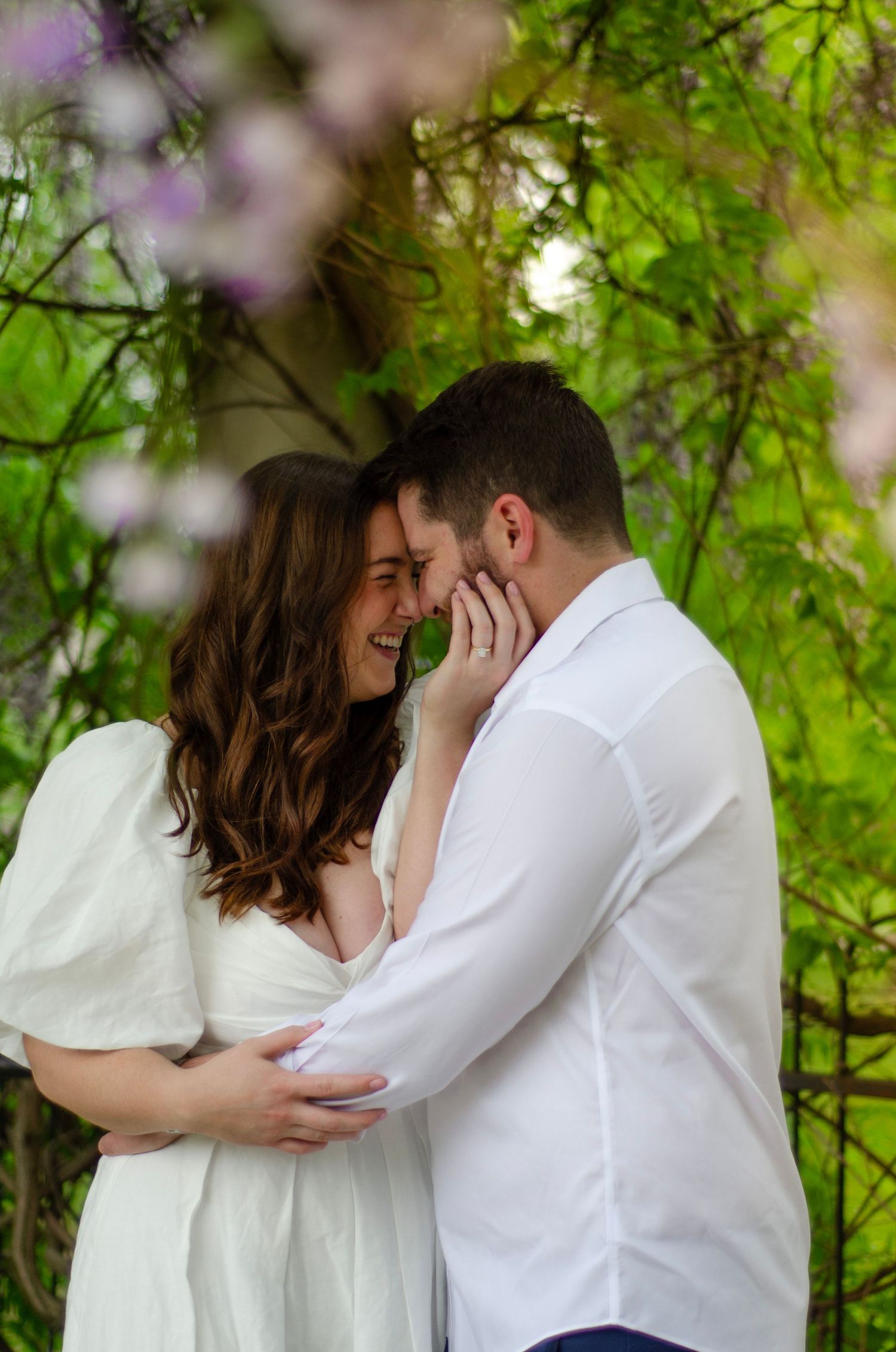 Tender embrace captured under blooming spring foliage with purple flowers.