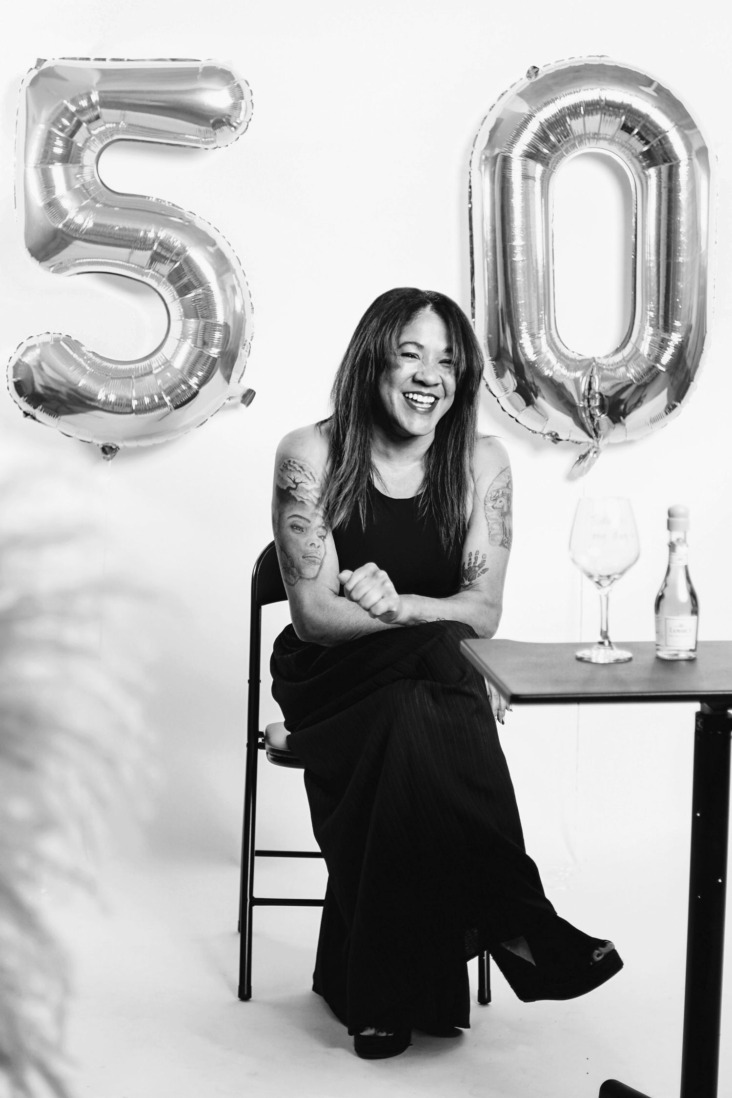 Silver number balloons spelling out 50 with a wine glass and bottle on a table.