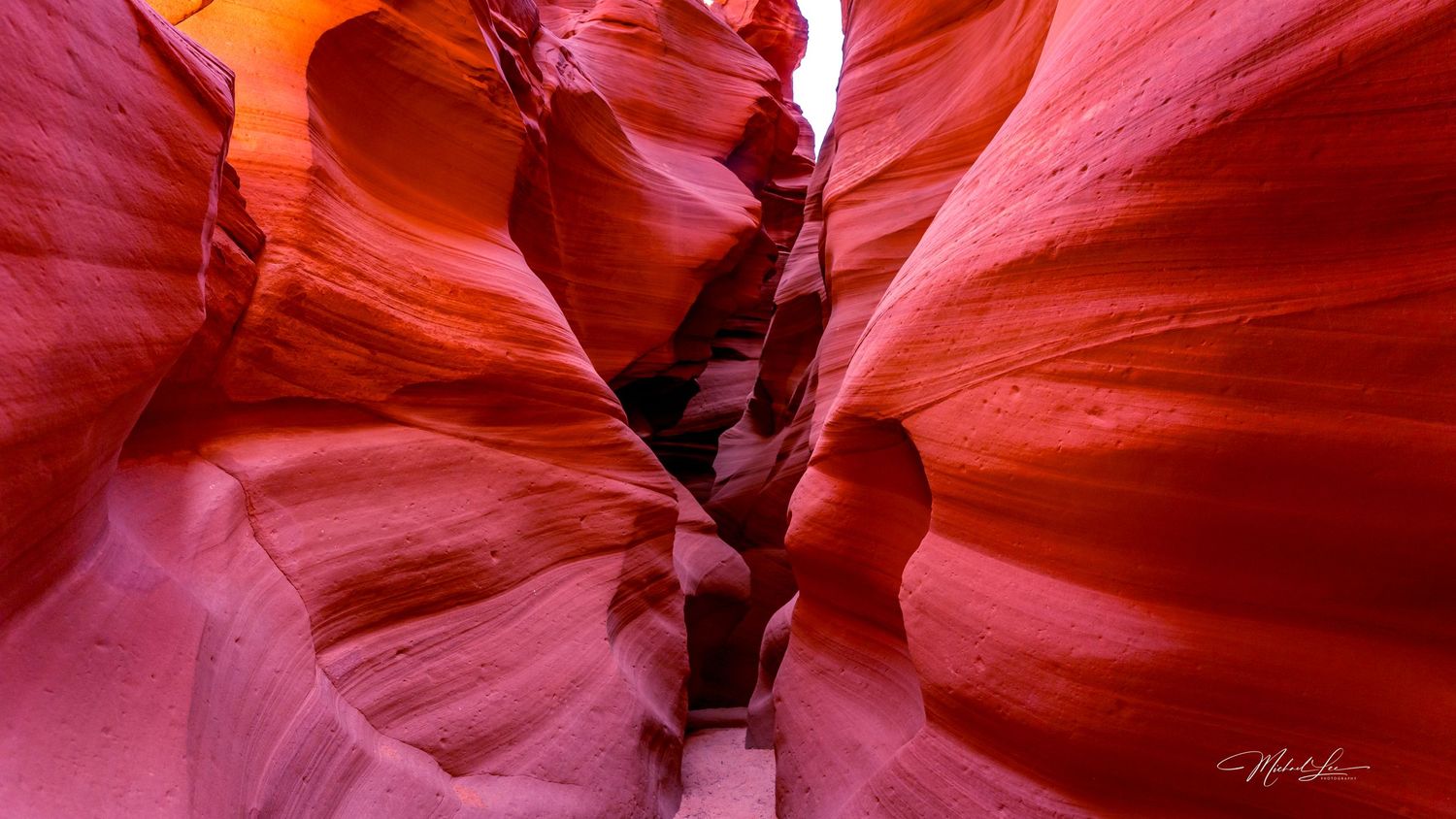 Vibrant red sandstone walls of a narrow slot canyon with smooth curved surfaces.
