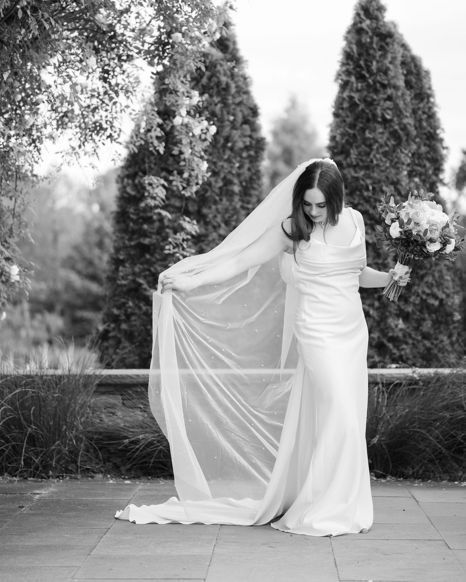 A sequence of black and white photos showing a flowing white dress being twirled against an outdoor garden backdrop.
