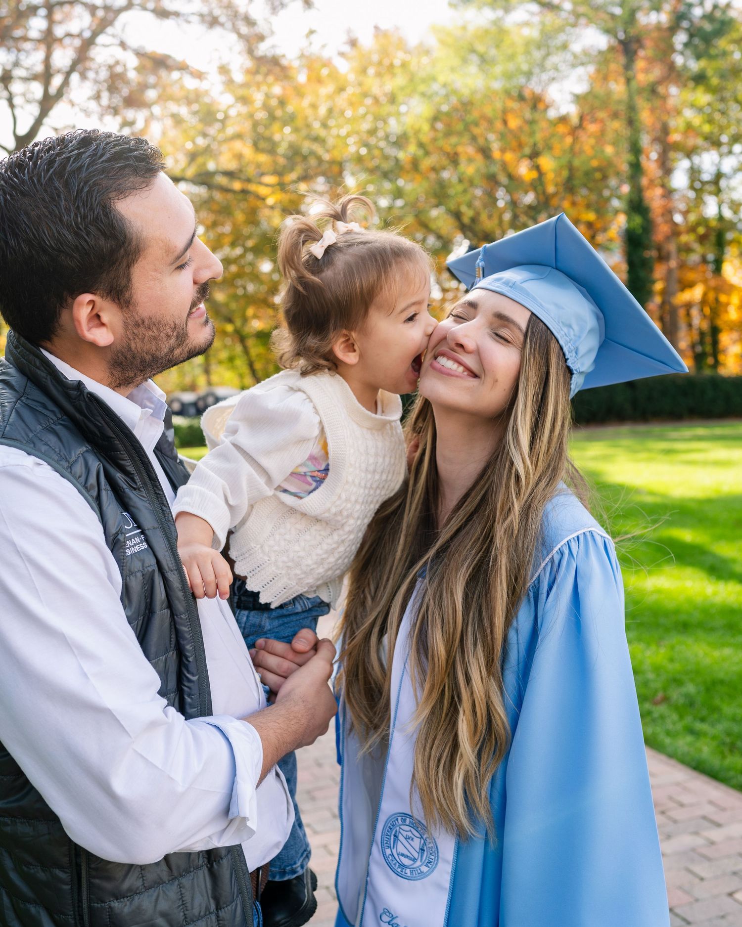 Family sharing joyful moments together outdoors during autumn with colorful fall foliage in the background.