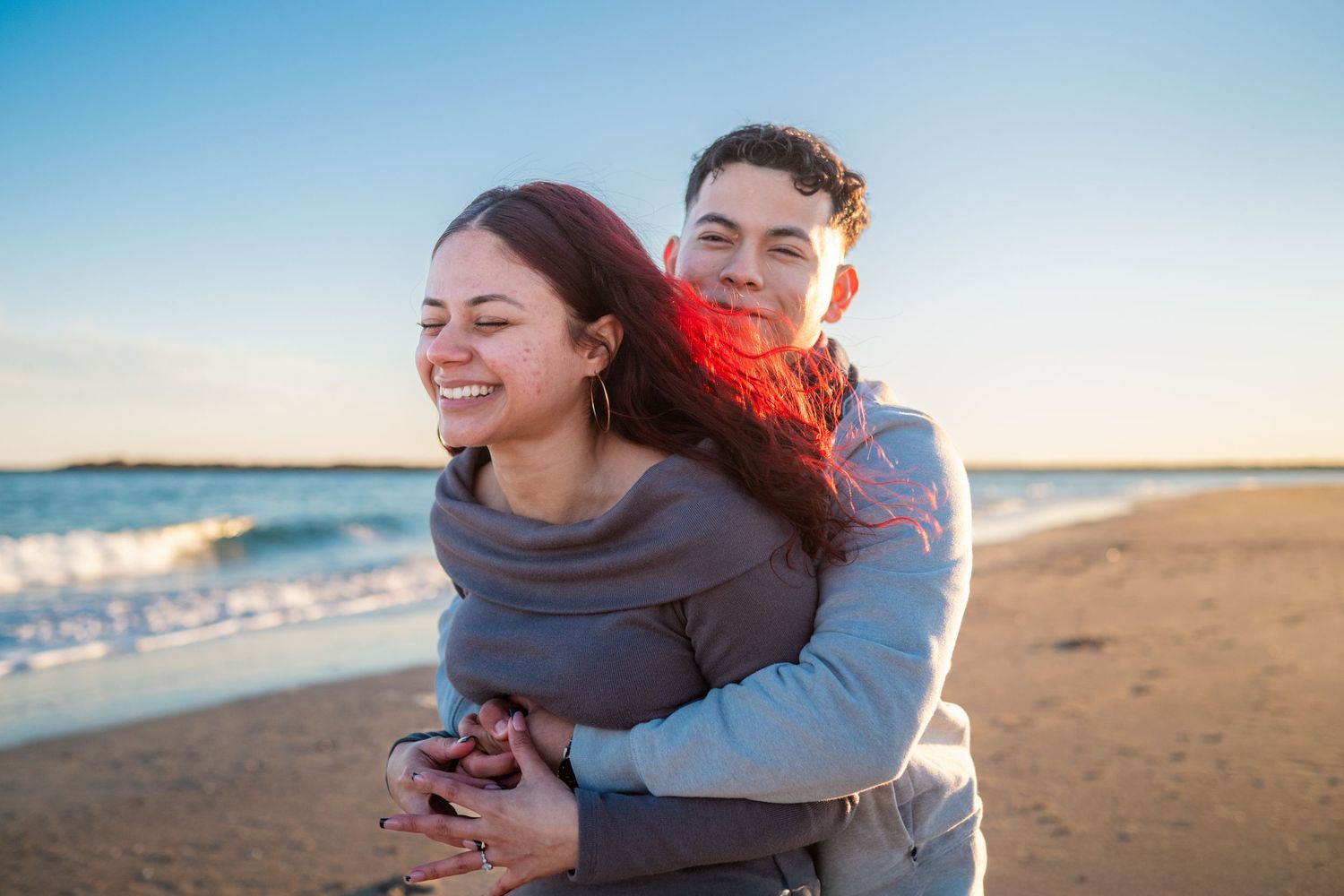 Couple sharing tender embraces and romantic moments on a sandy beach at sunset.