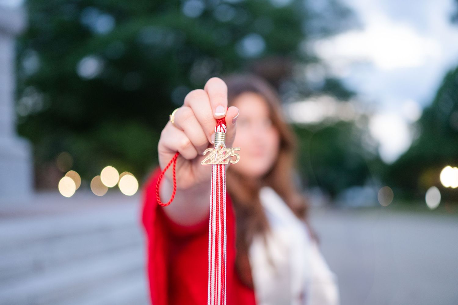 A sparkler creates a bright trail of light against a blurred outdoor background at dusk.