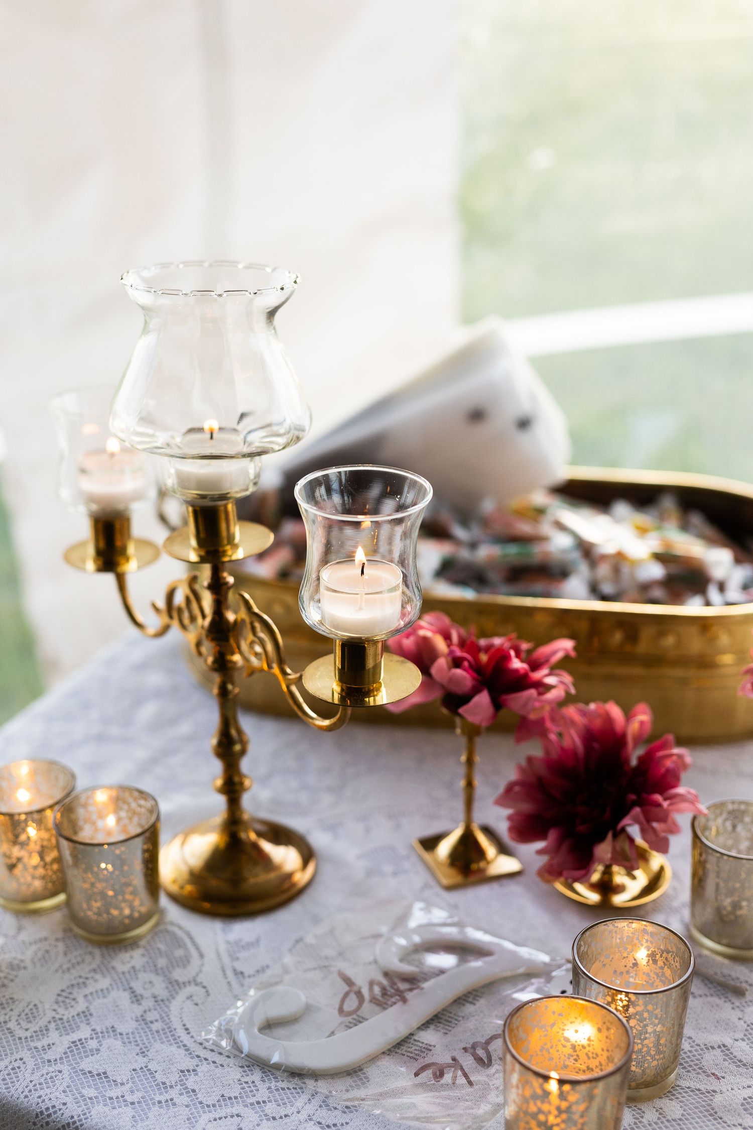 Gold candelabra and mercury glass votives with burgundy dahlias decorate wedding reception table.