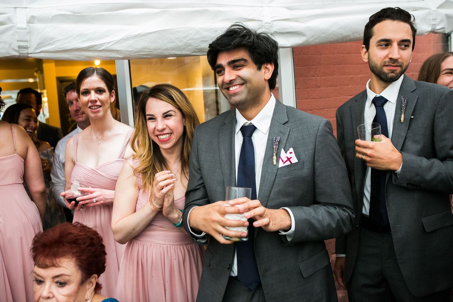 Wedding guests smiling and celebrating at an outdoor reception party.