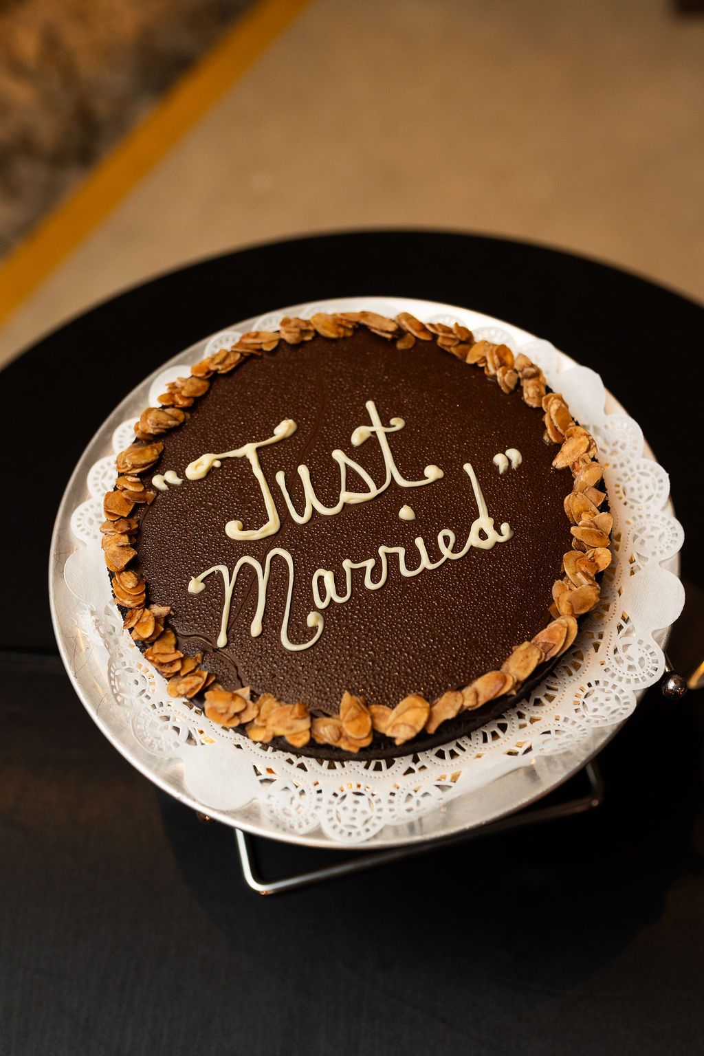 Chocolate wedding cake decorated with nuts and Just Married written in gold icing on top.