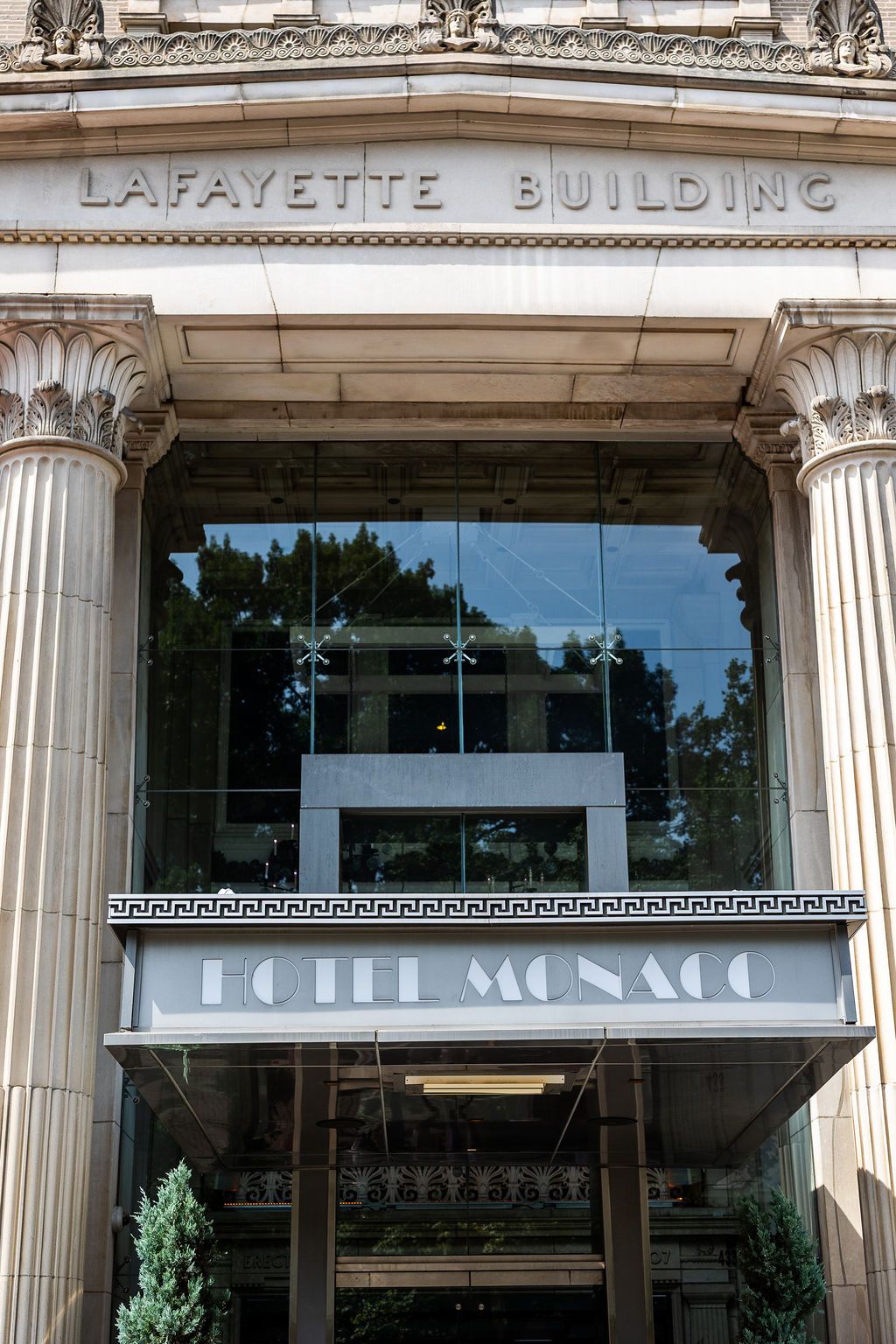 Exterior of Lafayette Building housing Hotel Monaco with classical columns and elegant stone facade.