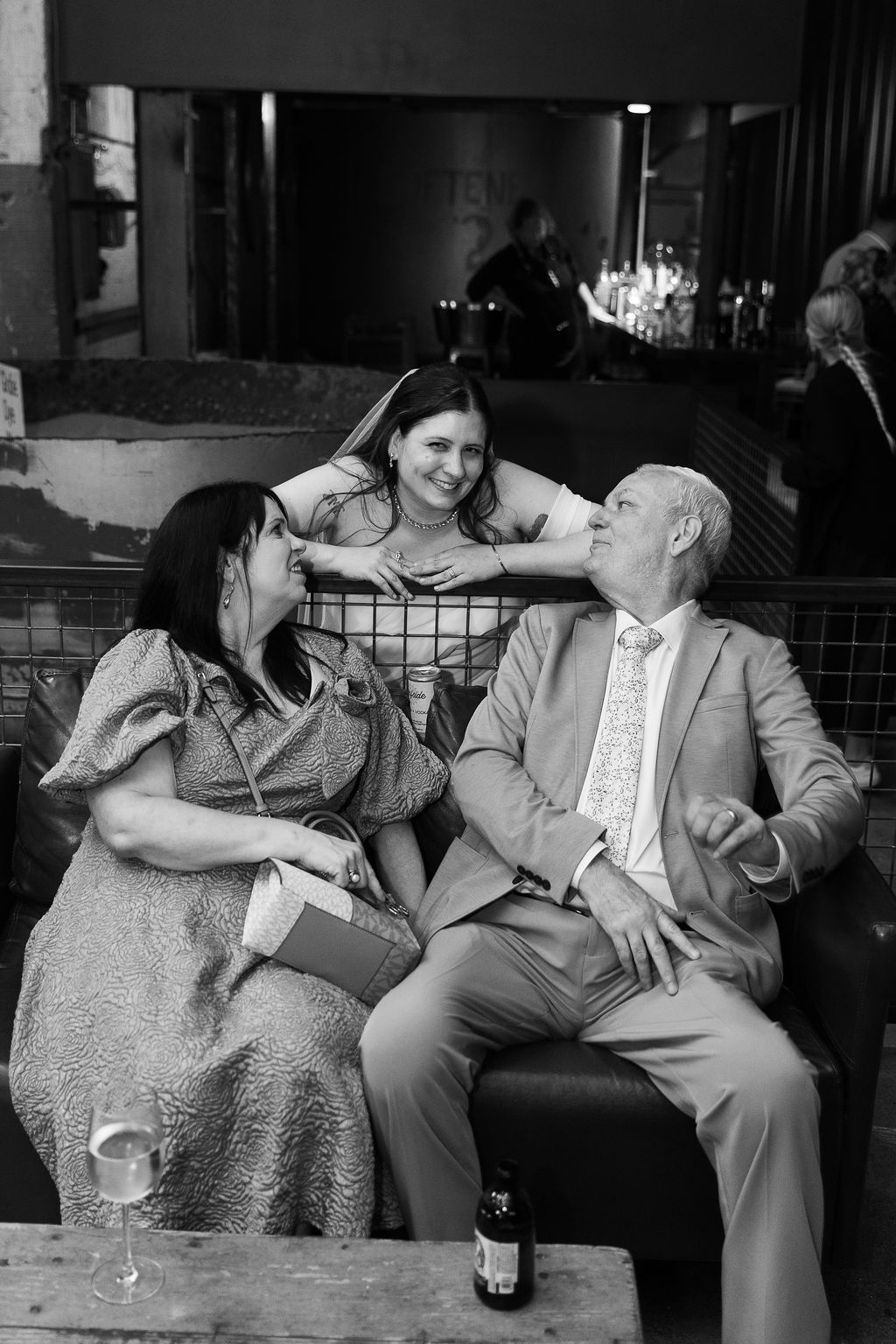 Black and white photo of three guests laughing together at an elegant indoor event.