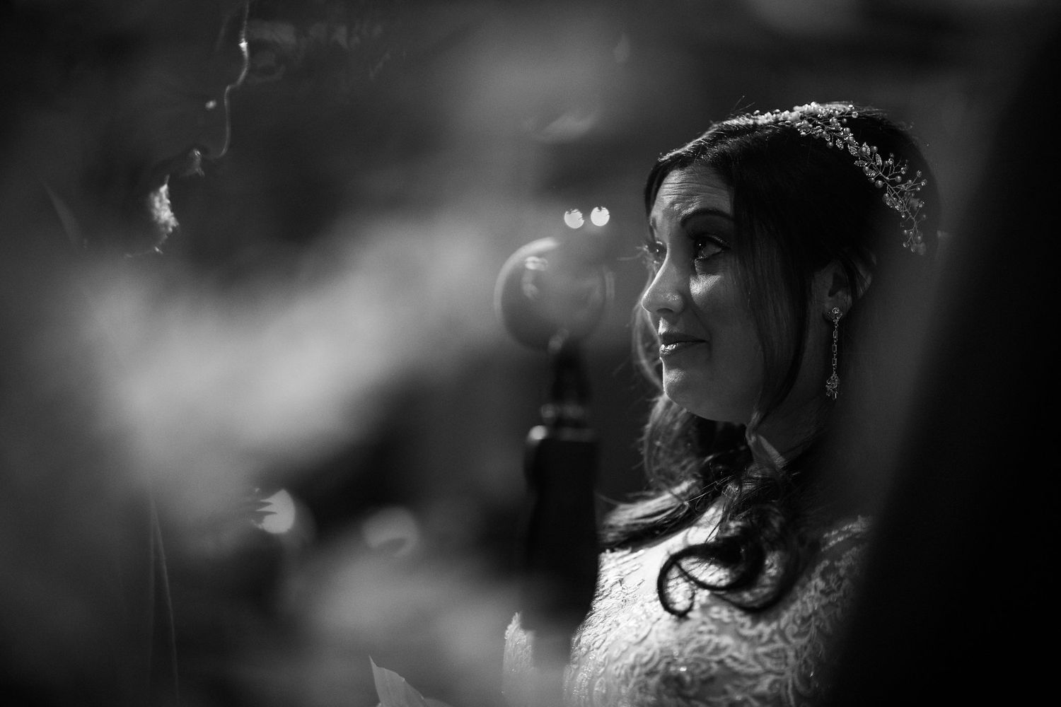 Black and white close-up portrait of radiant bride during wedding ceremony.