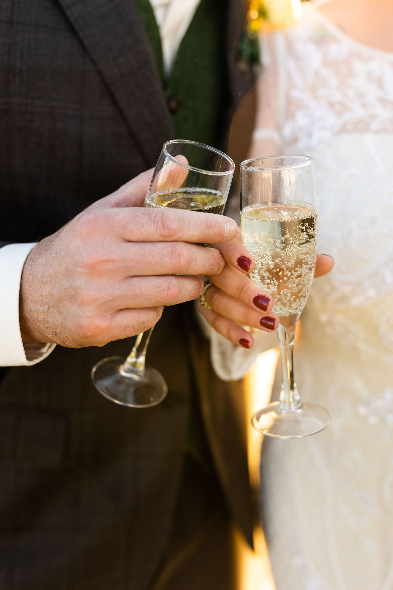 Close-up of bride and groom toasting with champagne flutes at outdoor wedding reception.