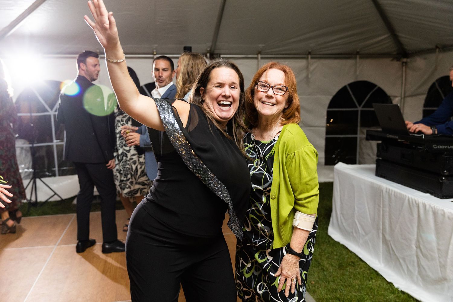 Two women laughing and celebrating together on the dance floor at a wedding reception.
