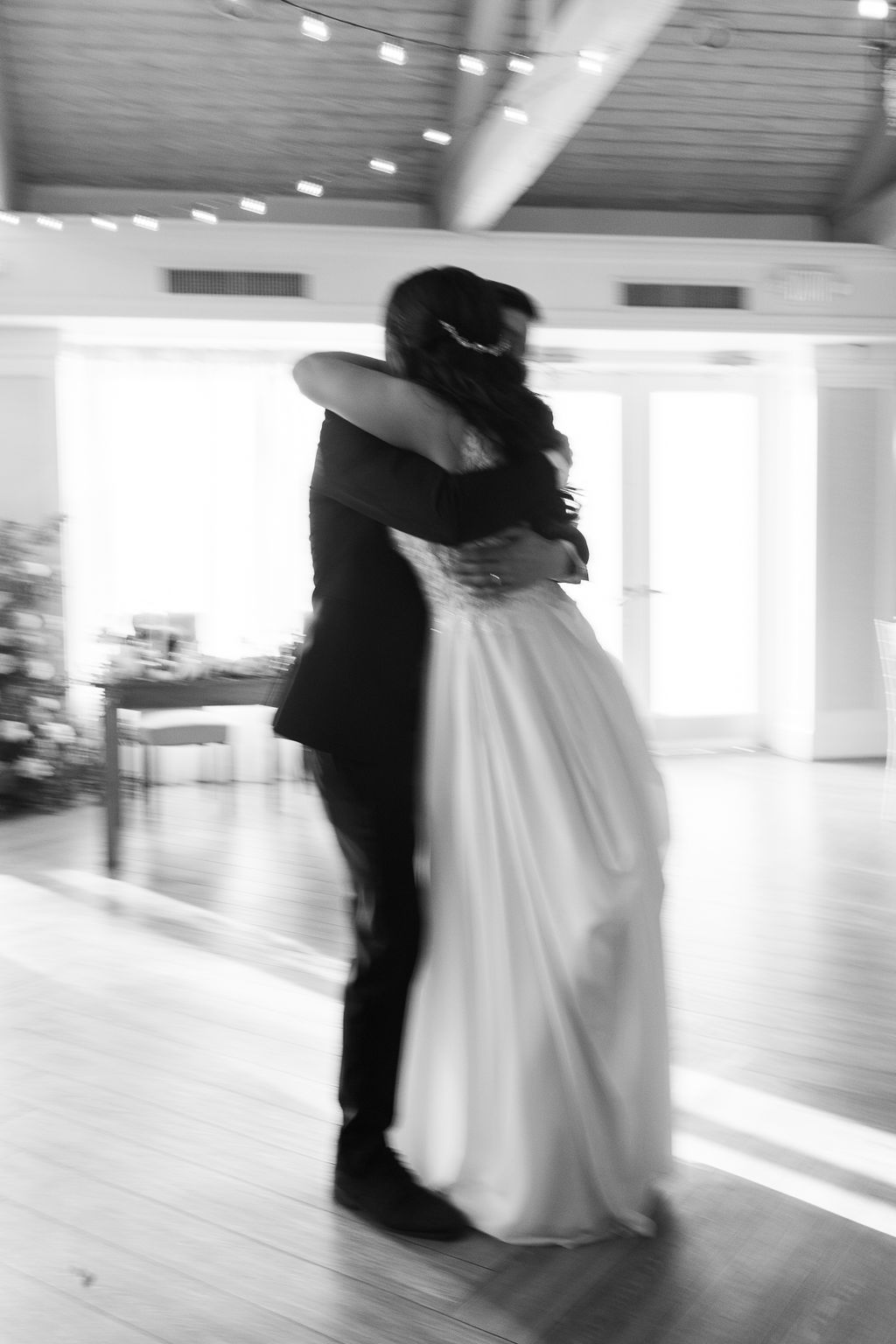 Artistic motion-blur black and white photo of bride and groom embracing during their first dance.