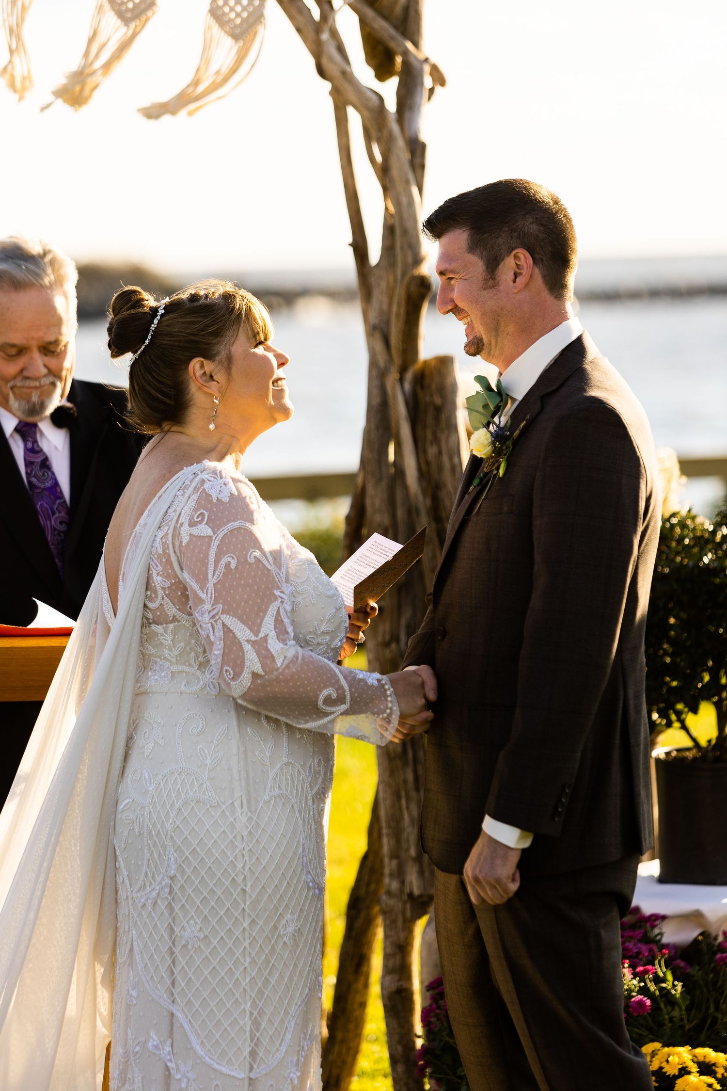 Bride and groom laughing joyfully while exchanging vows at golden hour outdoor wedding ceremony.
