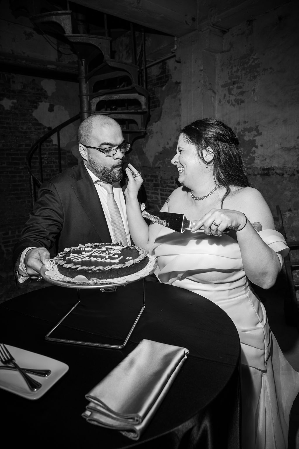 Black and white photo of bride and groom cutting their chocolate wedding cake together.