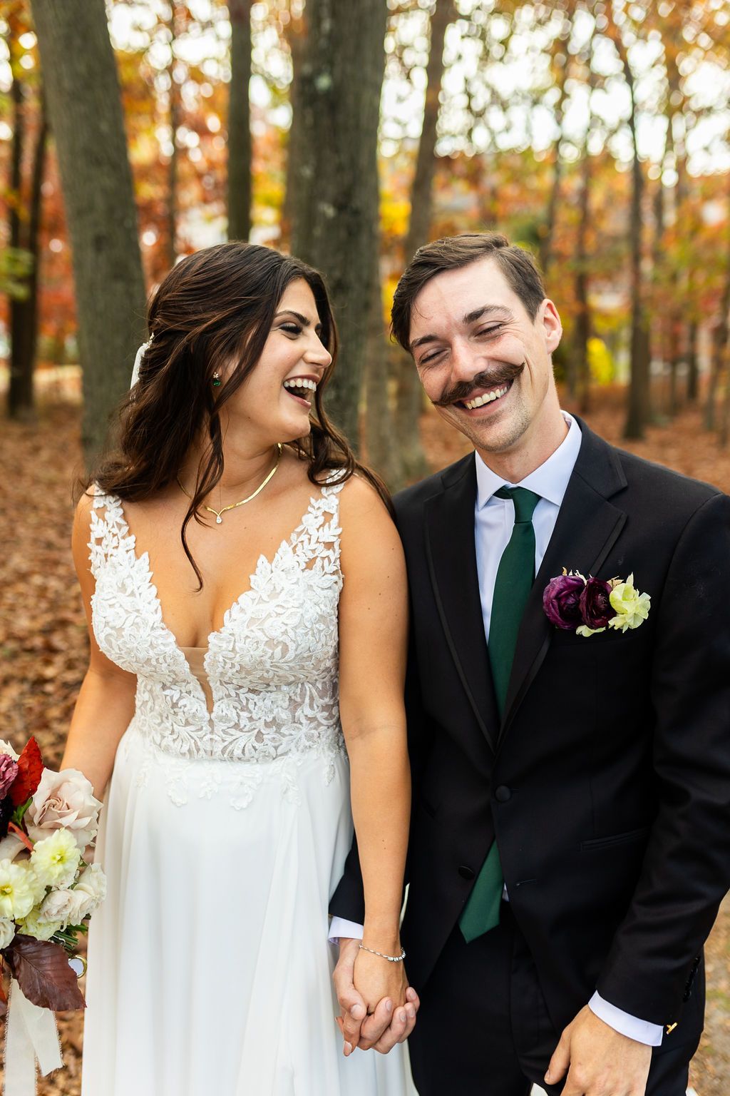 Bride and groom laughing together in autumn forest, groom with mustache.