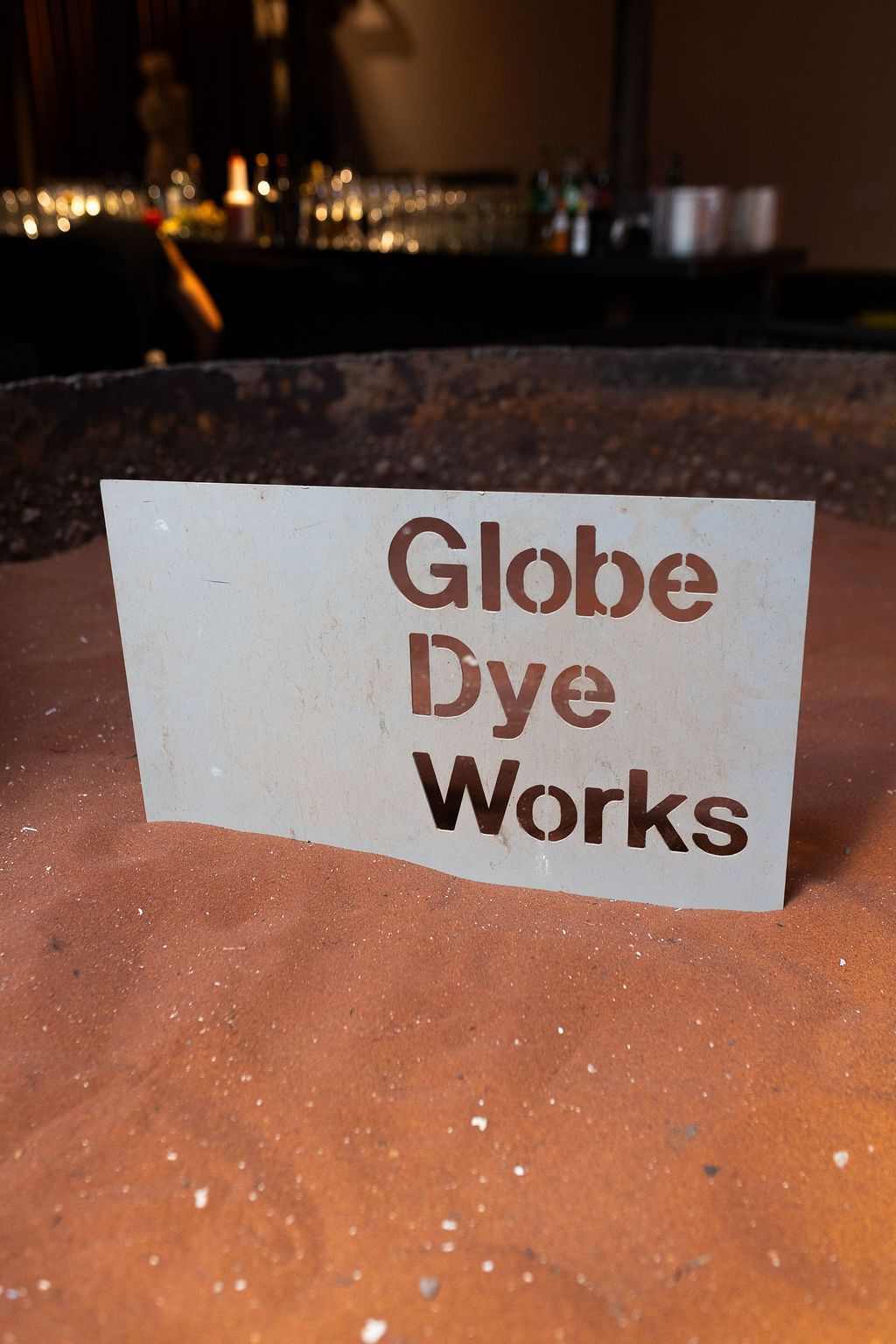 Globe Dye Works venue sign displayed on rustic terracotta surface with bar in background.
