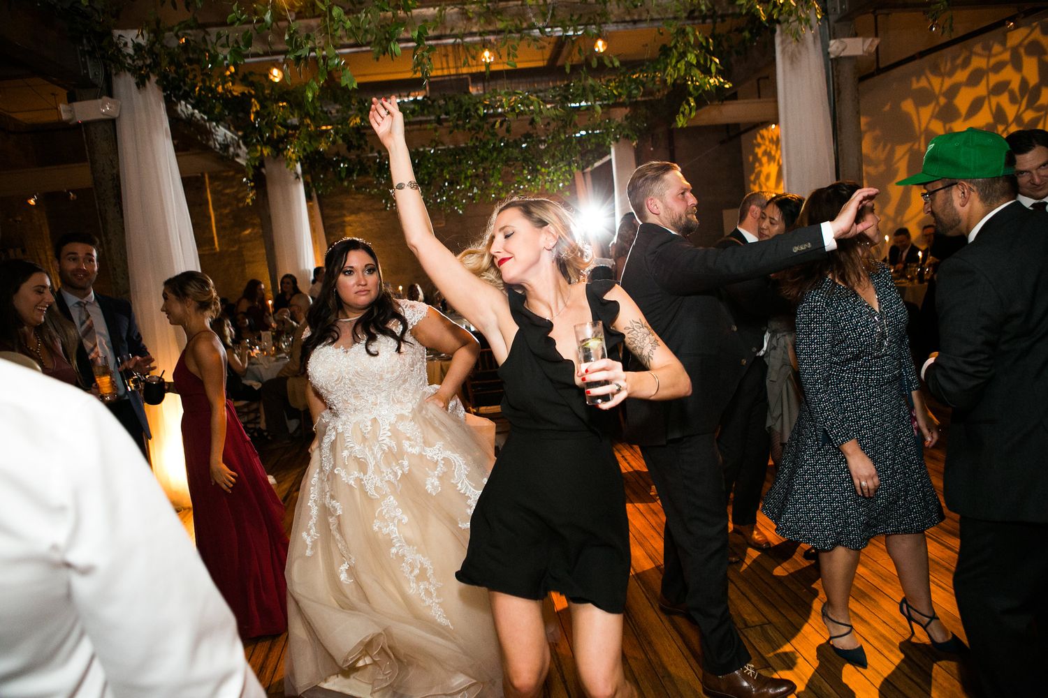 Bride in white gown dancing with guests at wedding reception.