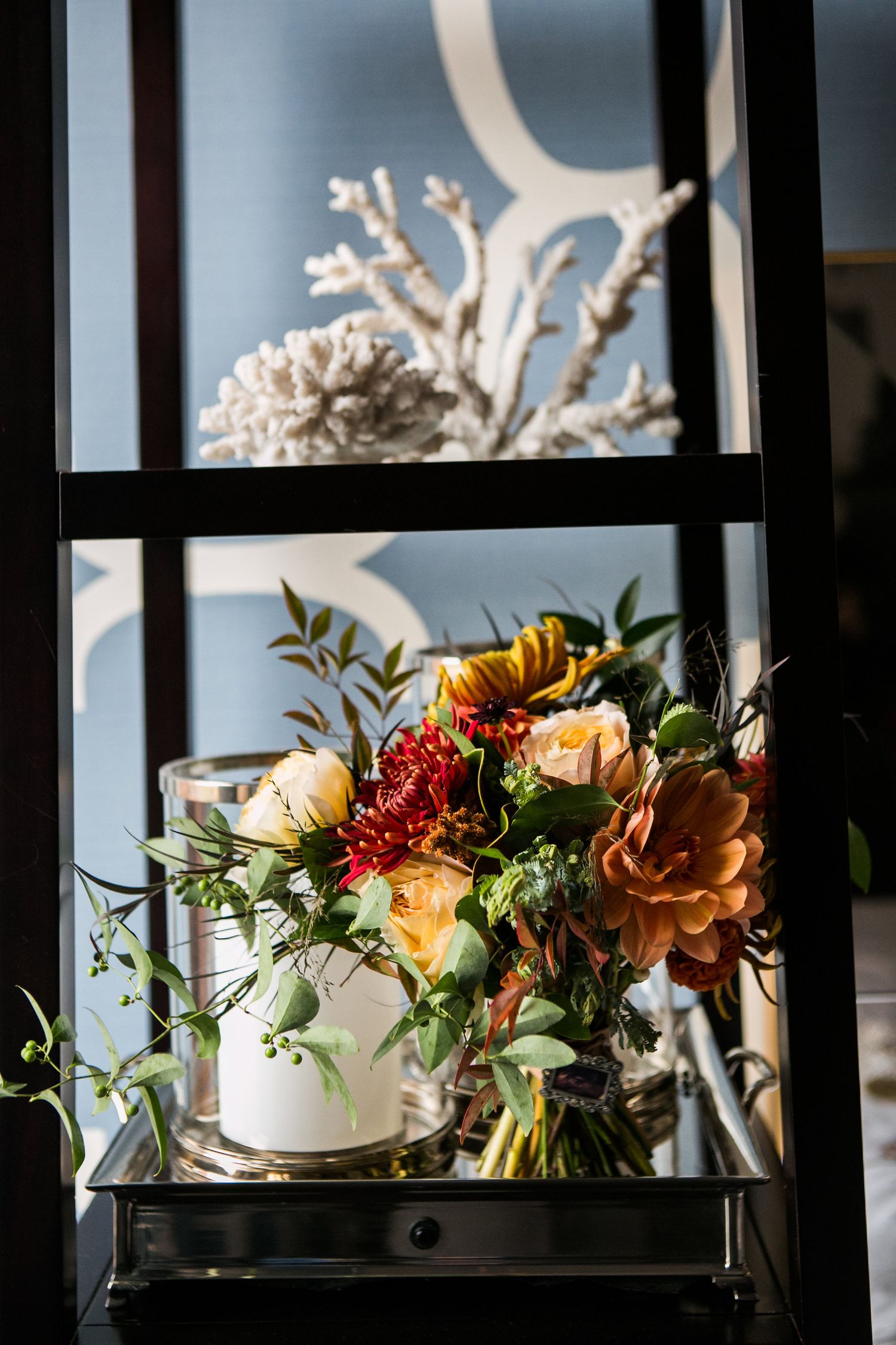 Elegant autumn wedding floral arrangement with dahlias and mixed blooms on decorative shelf.
