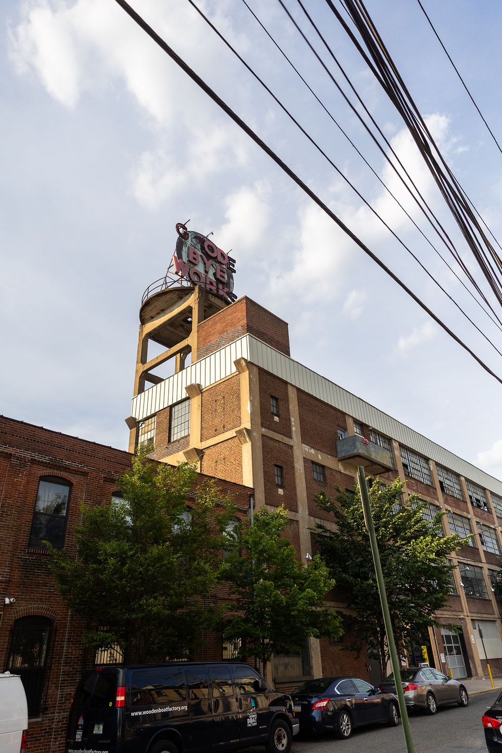 Exterior of historic Globe Dye Works brick building with vintage signage and power lines against a cloudy sky.