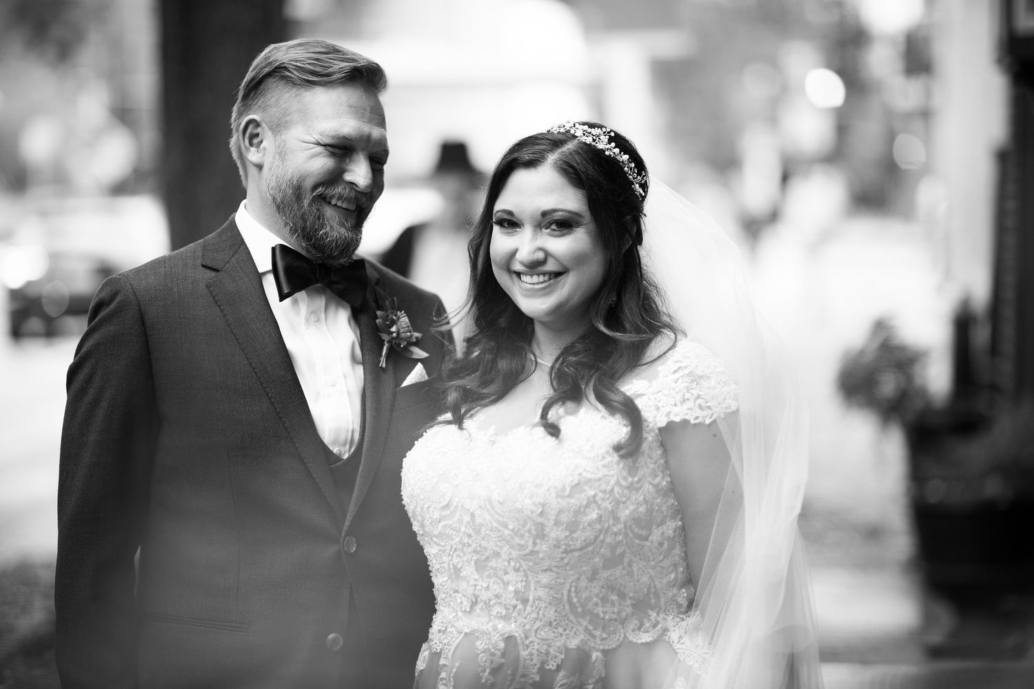 Black and white portrait of smiling bride and groom on their wedding day outdoors.