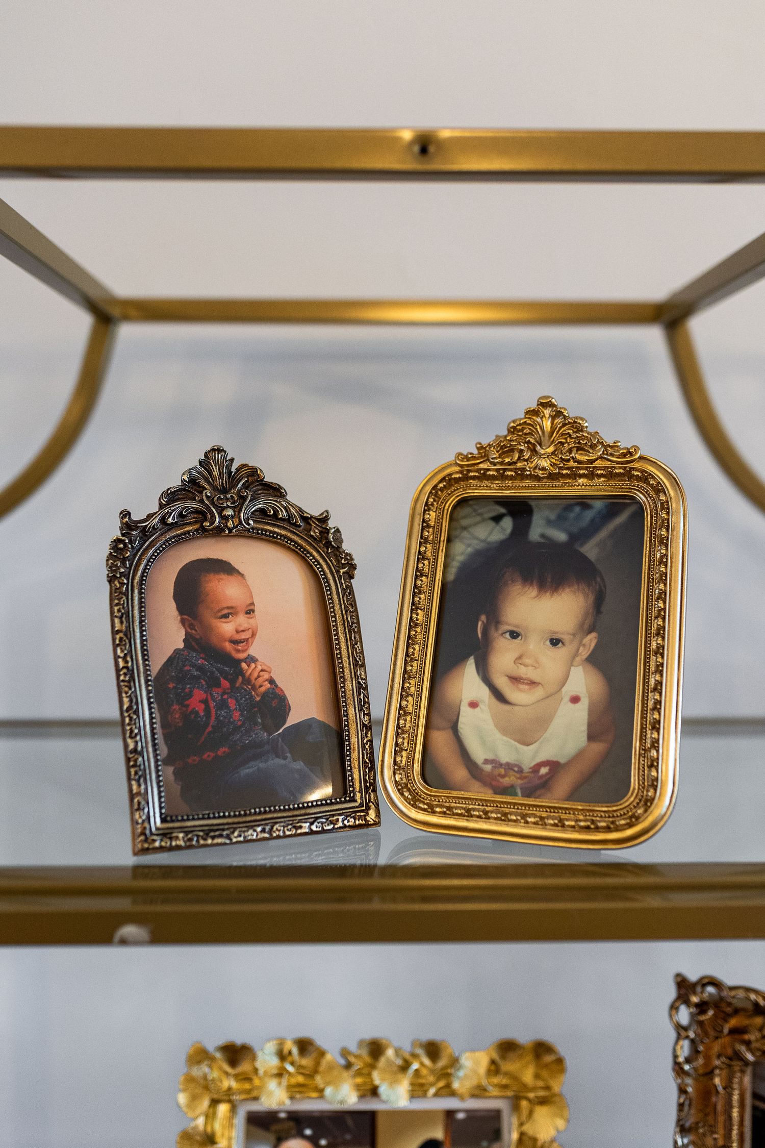 Two gold-framed childhood photos of the bride and groom displayed on a glass shelf.