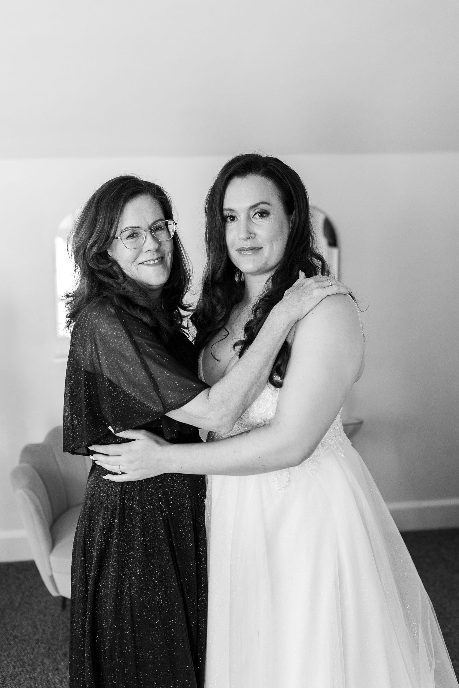 Black and white photo of two women embracing warmly in bright indoor setting.