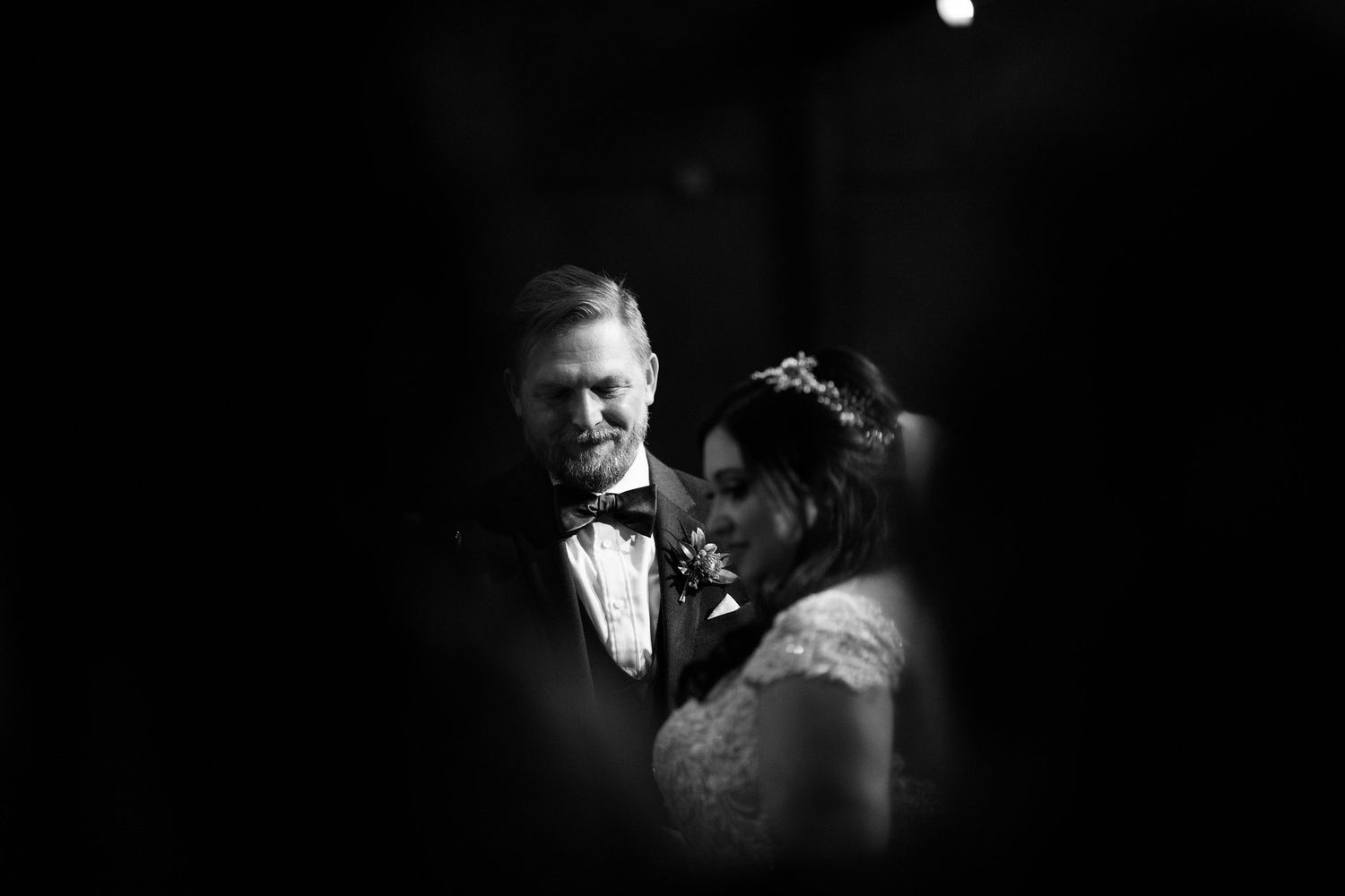 Intimate black and white portrait of bride and groom sharing a tender moment.