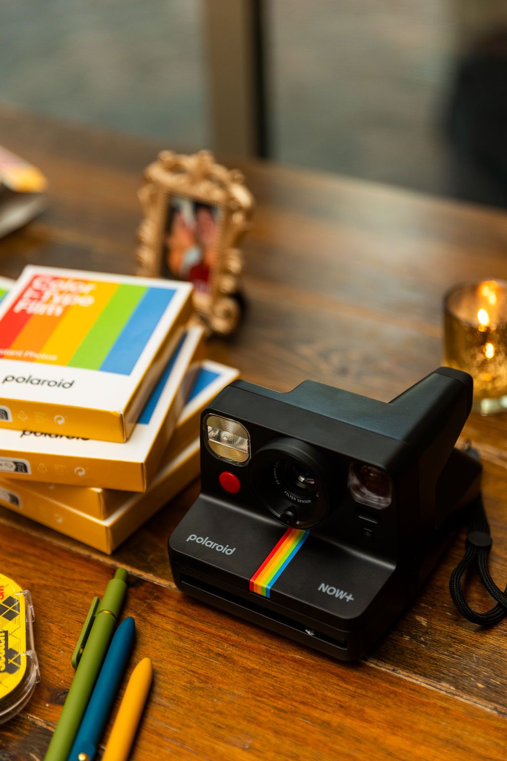 Polaroid Now+ instant camera with film boxes on wooden table at wedding reception photo station.